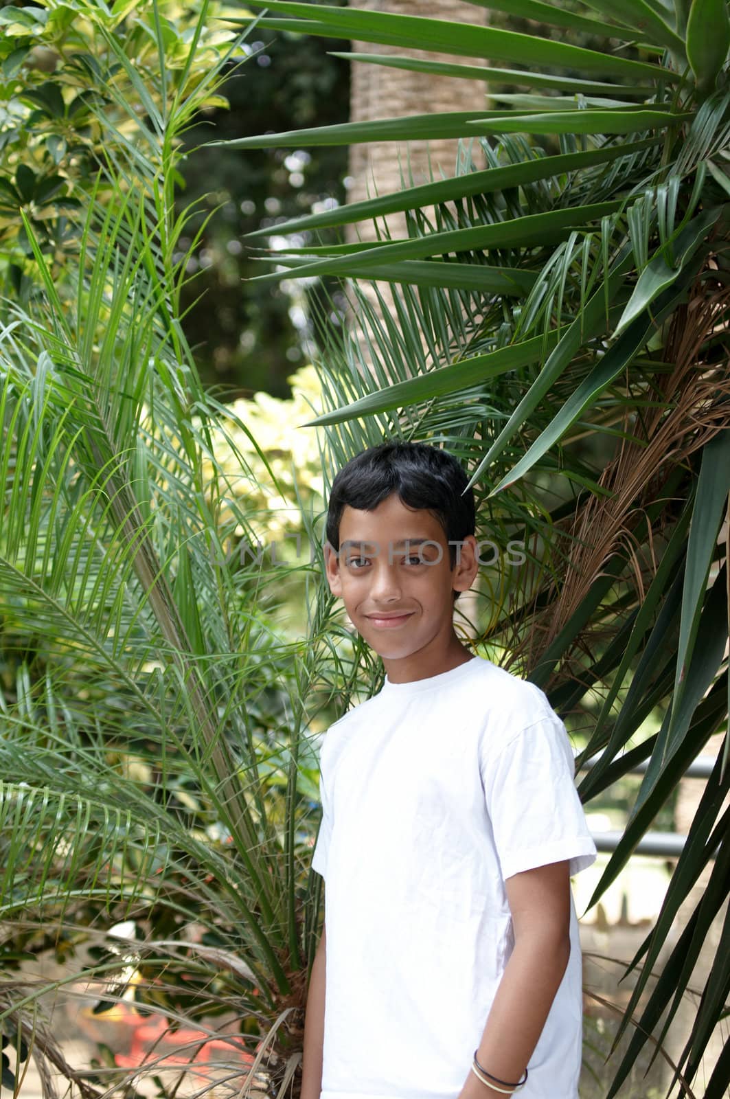 Portrait of a smiling boy in the background of tropical plants.