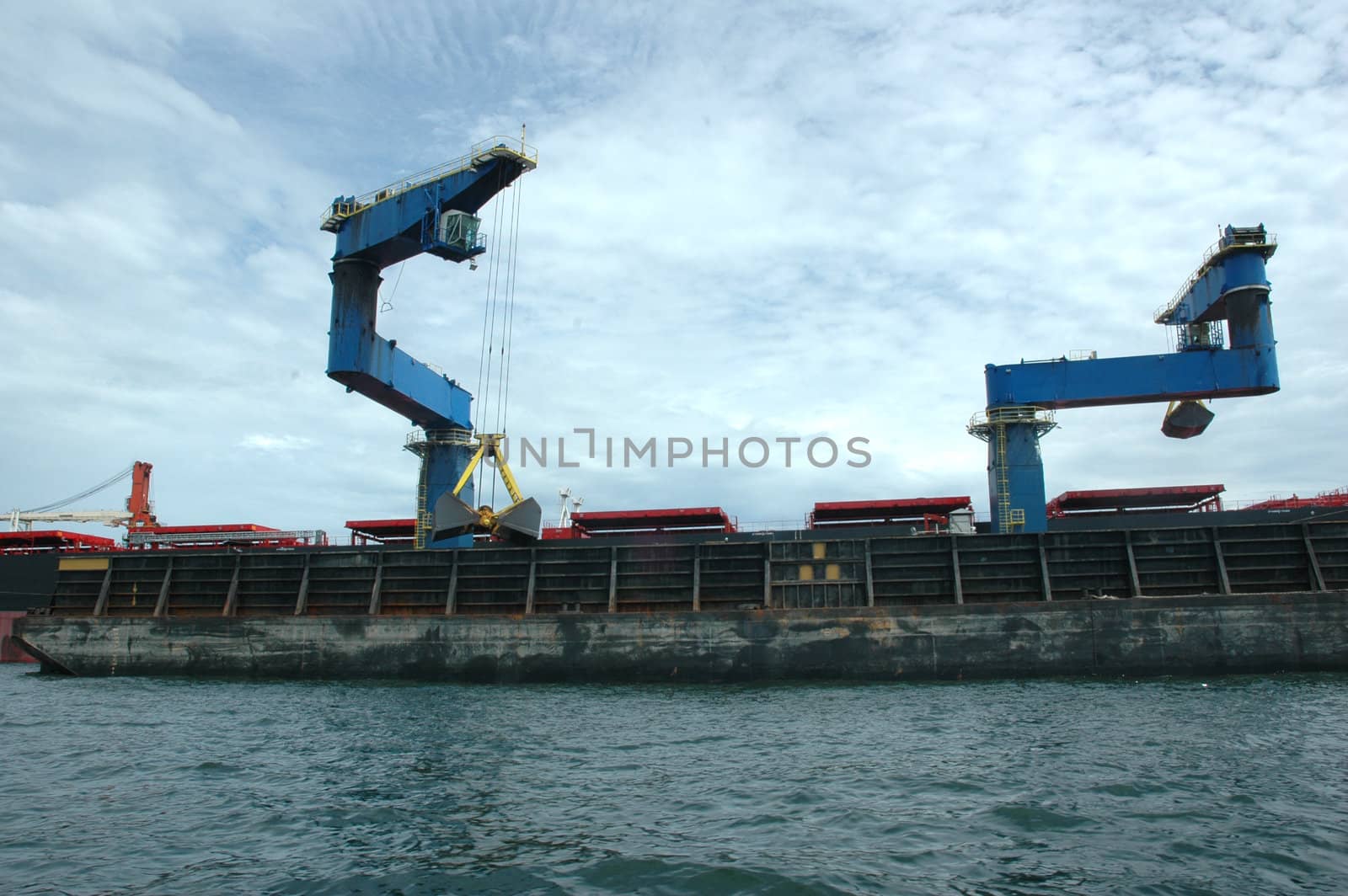 coal is being loaded onto tankers with a blue crane from a pontoon by antonihalim