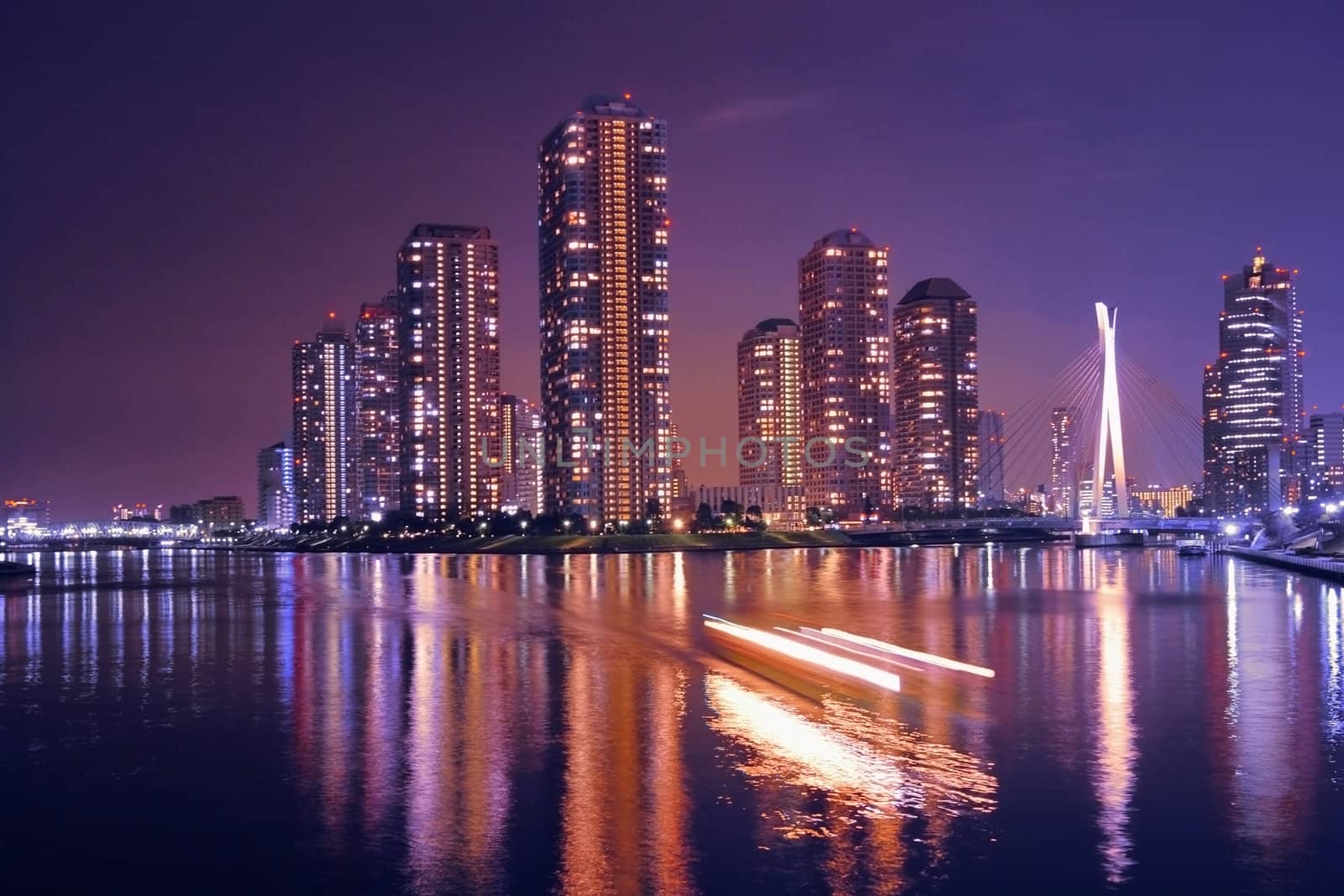  modern Tokyo buildings with night reflection in water and light traces of moving ship, Japan