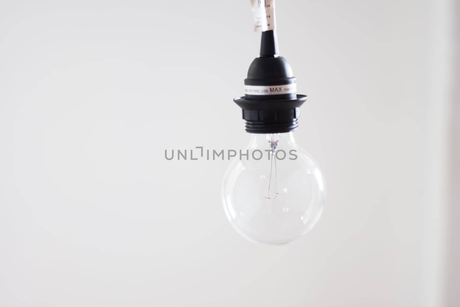 Clear hanging lightbulb against bright white background