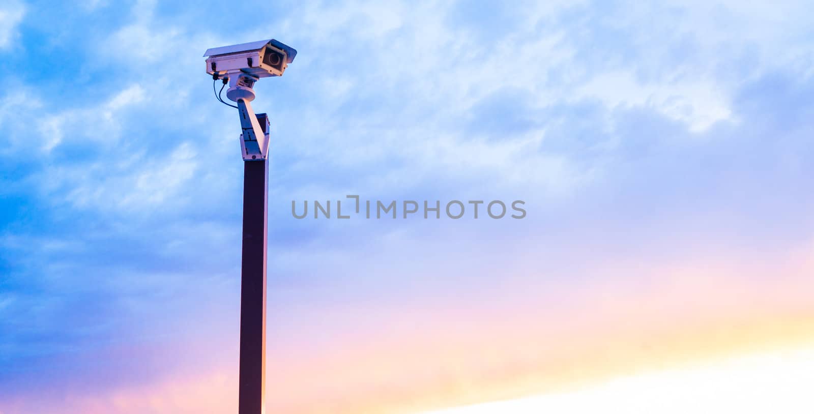 Urban security video camera outdoors at sunset