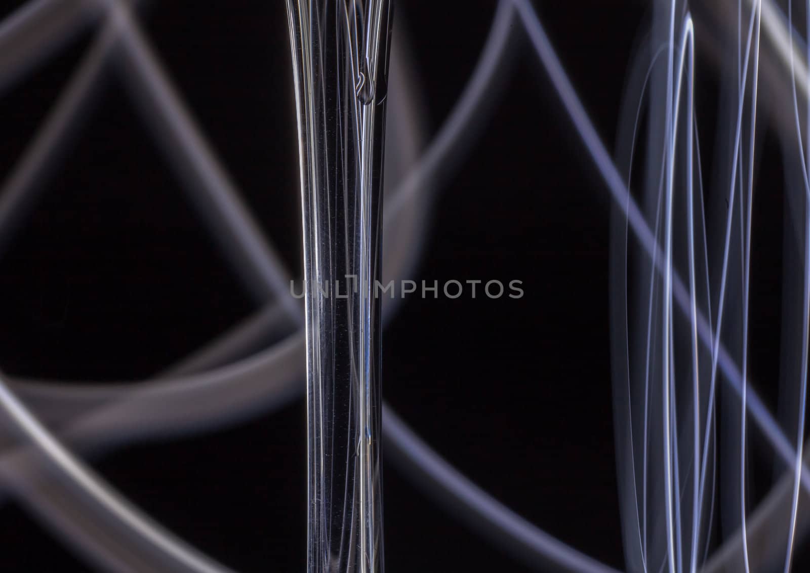 Abstract light tracks behind drinking glass on black