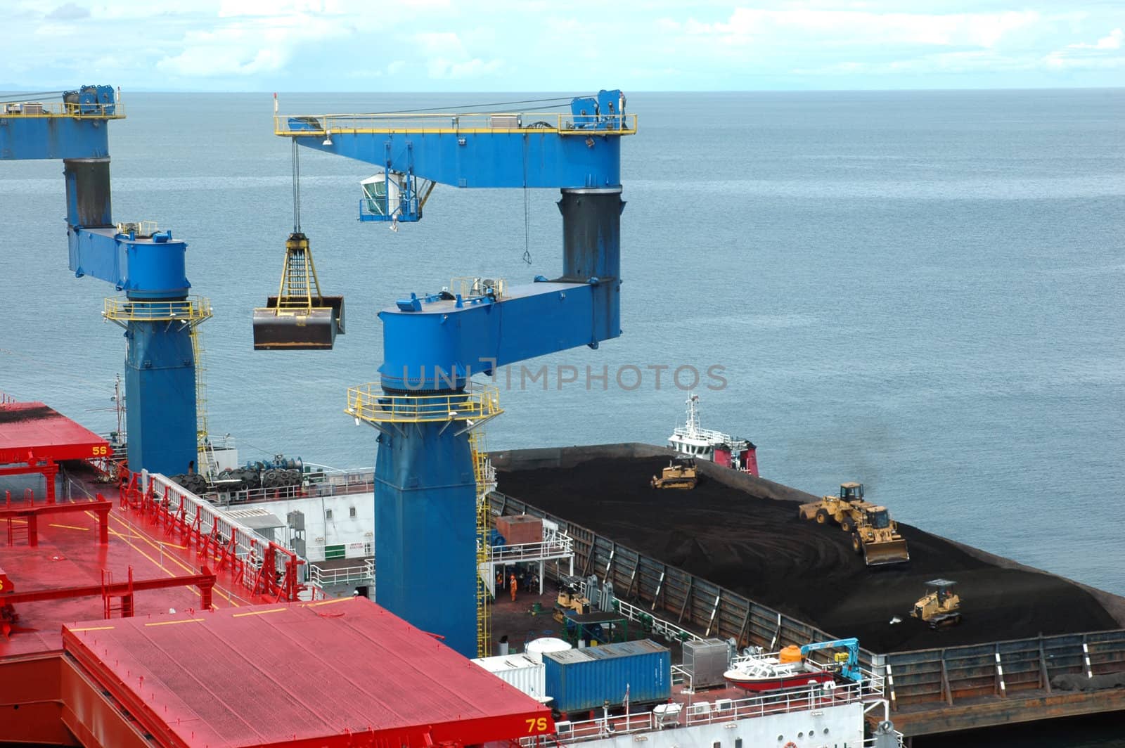 coal is being loaded onto tankers with crane from a pontoon