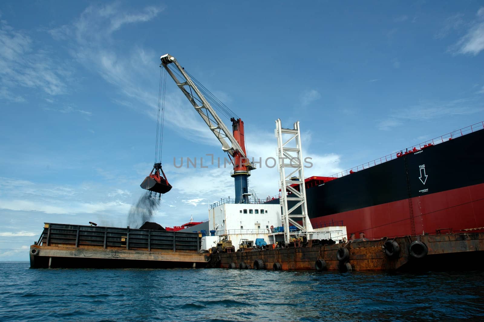 coal is being loaded onto tankers with a crane by antonihalim