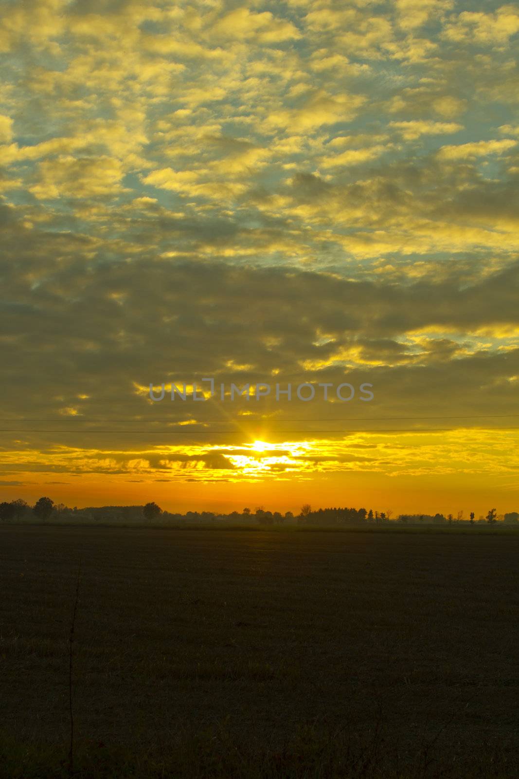 A beatiful sunset with cloudy sky over the fields