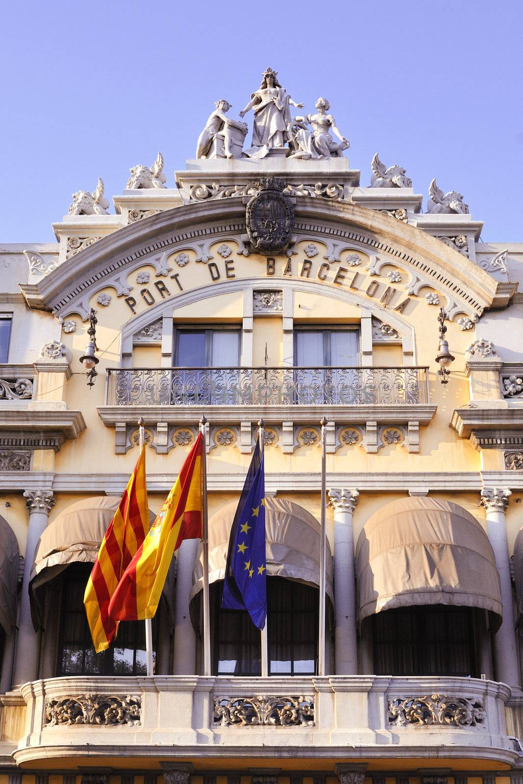 historic building of famous Barcelona port with Spanish, Catalan and European Union Flags on it