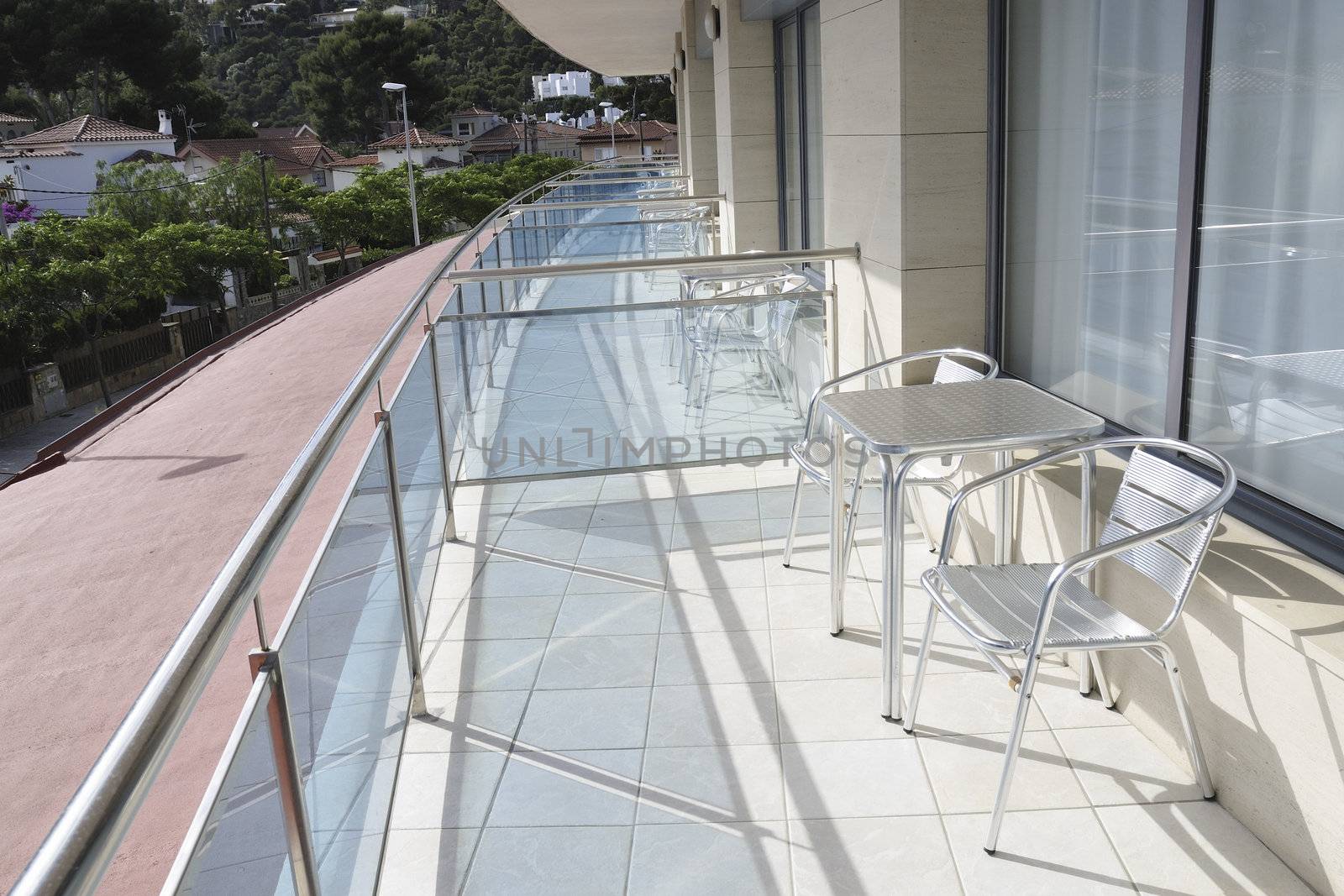 sunny bright open air terrace with glass fence in summer resort