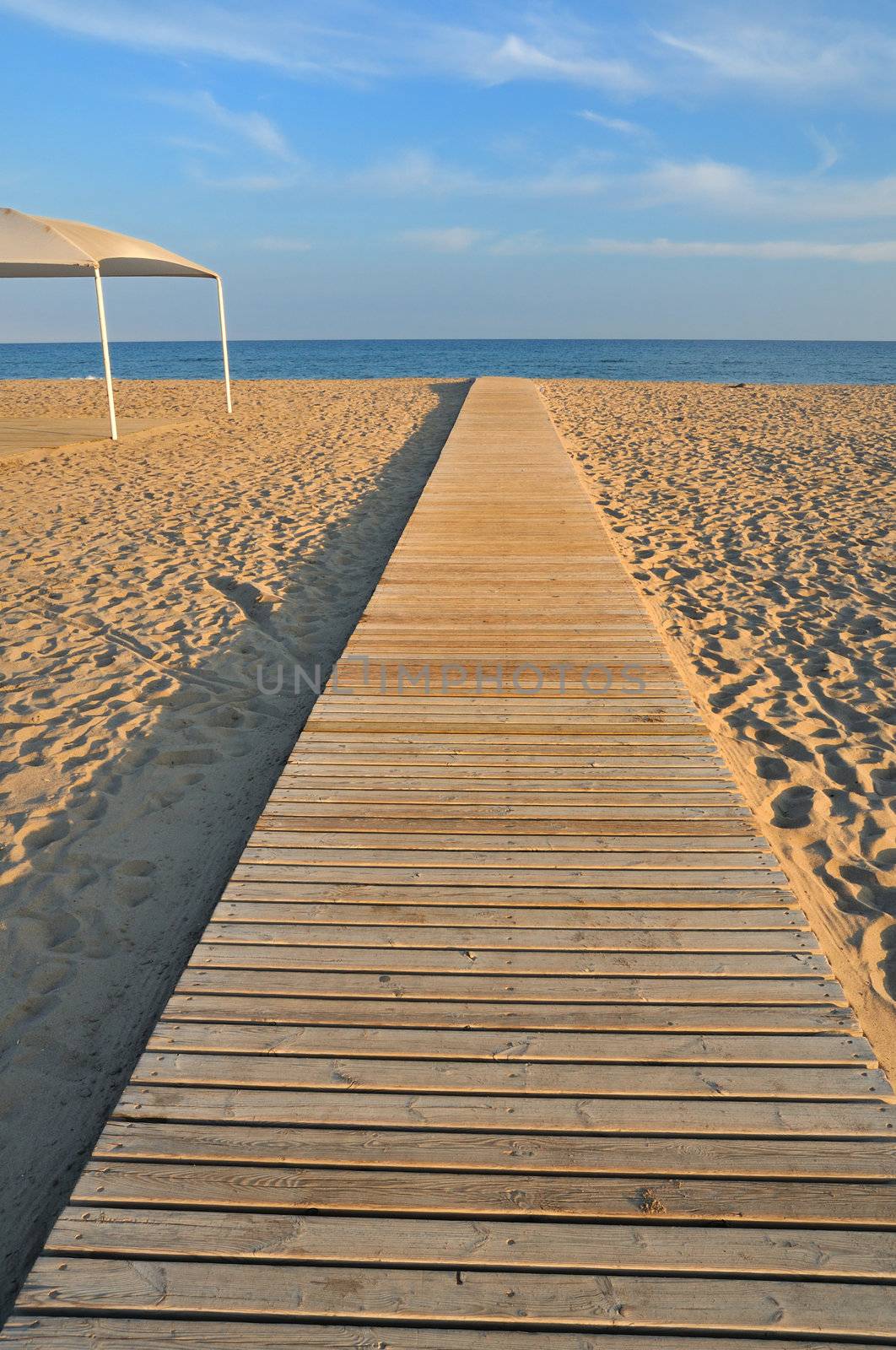straight wooden pathway on empty evening beach in Spain