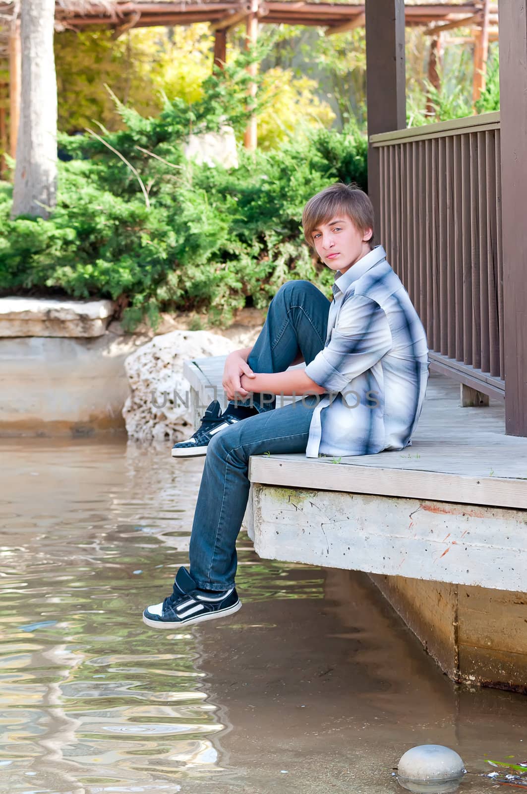 Portrait of a teenager on a background of water in the park.