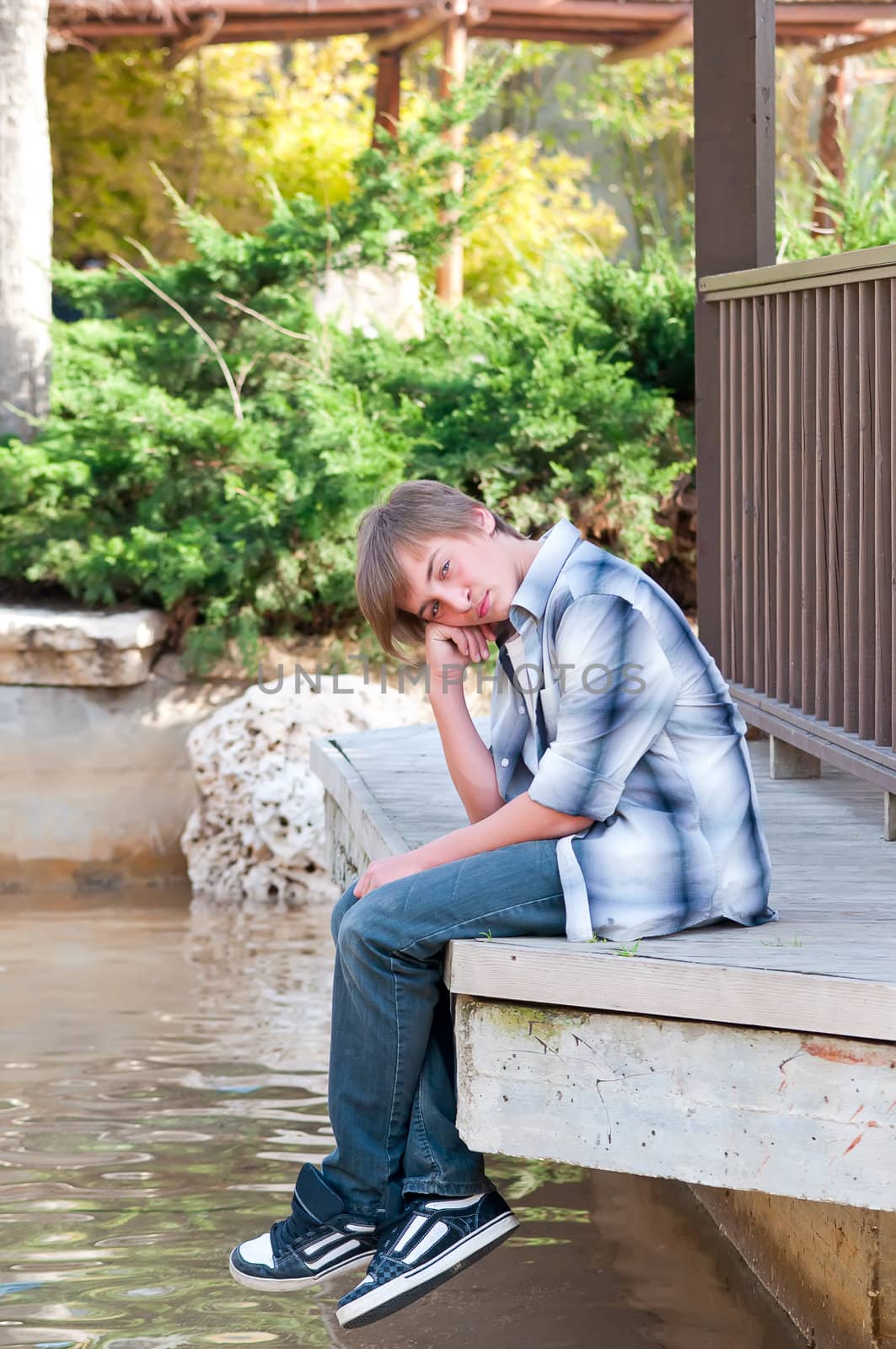 Portrait of a teenager on a background of water in the park.