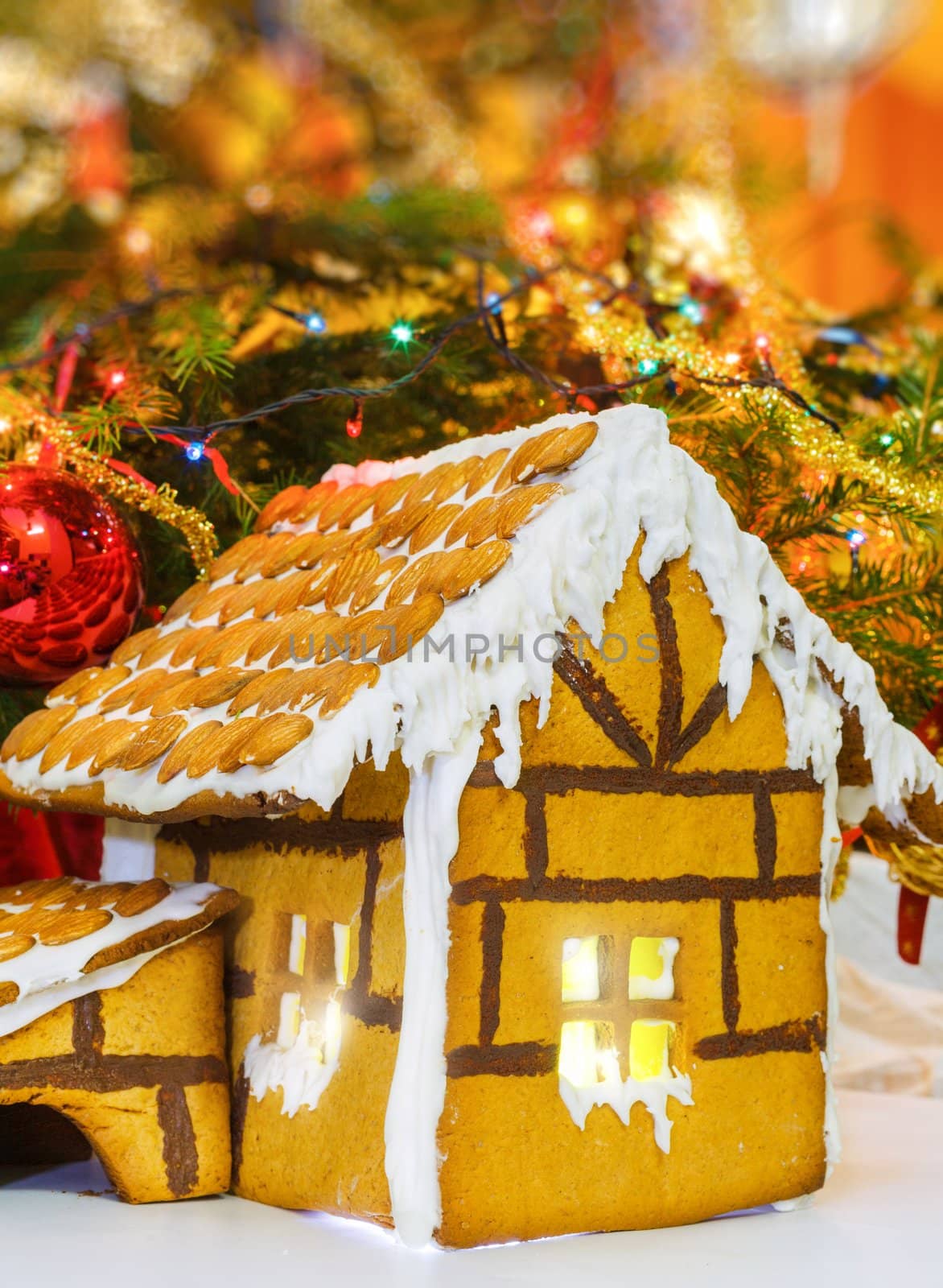 Christmas gingerbread house decoration on background of defocused christmas tree. Hand decorated. Vertical view