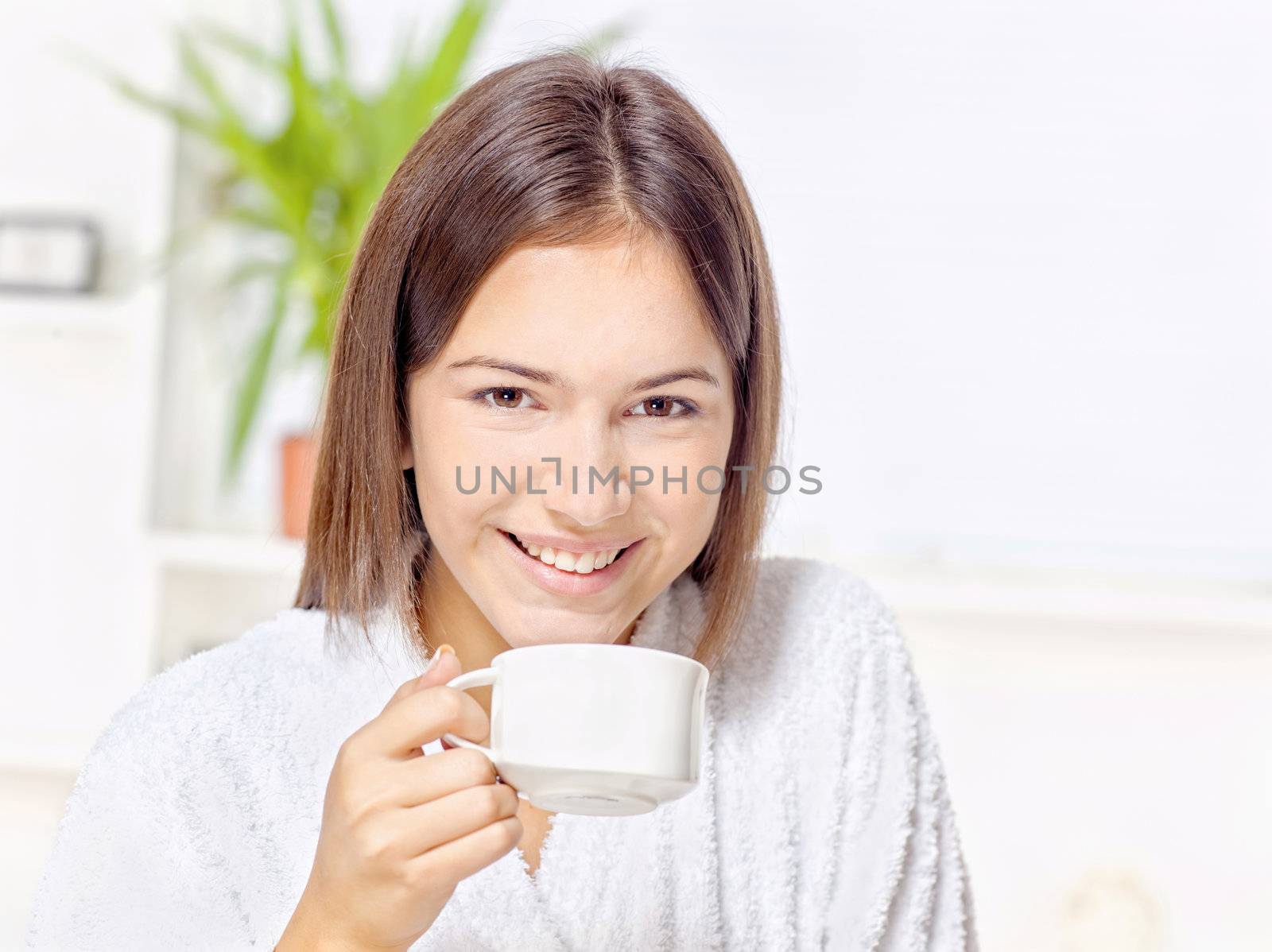 Woman in bathrobe holding cup at home