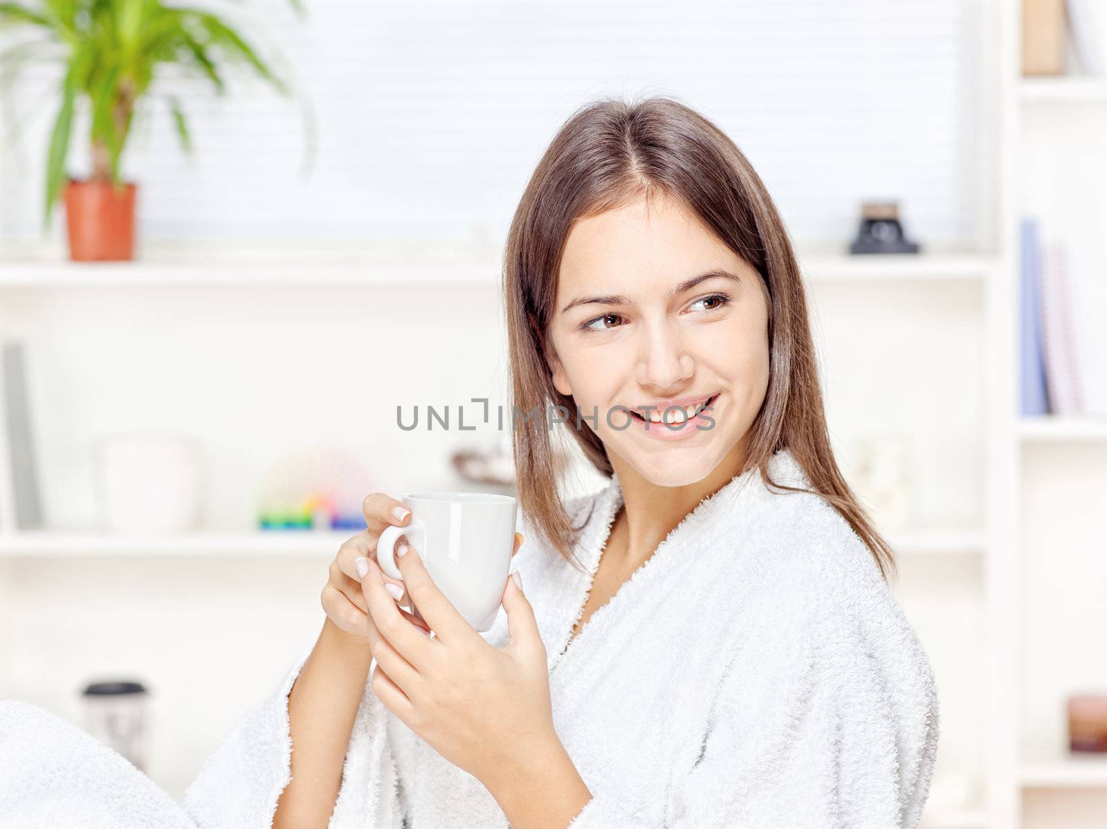 Woman in bathrobe holding cup at home