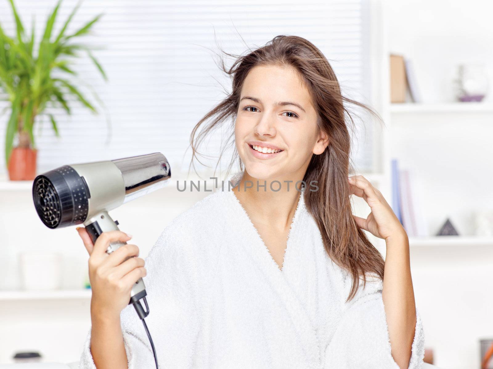 Young woman drying hair at home