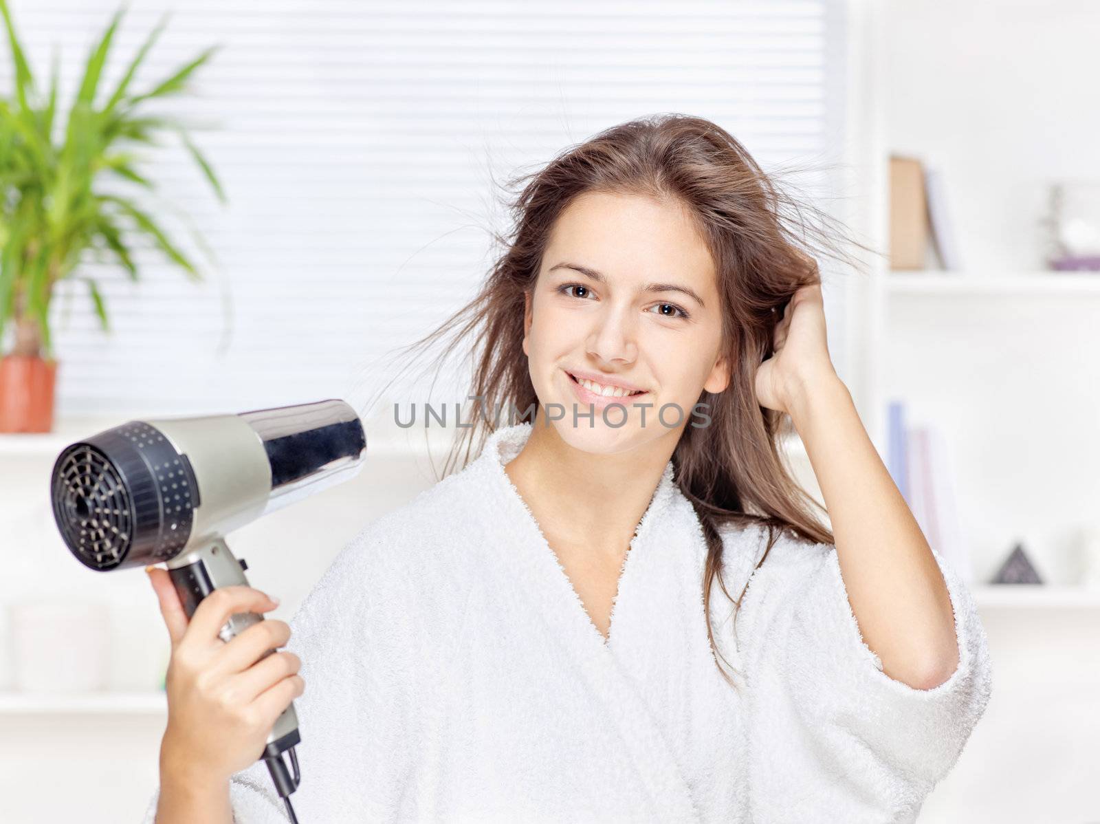 Young woman drying hair at home