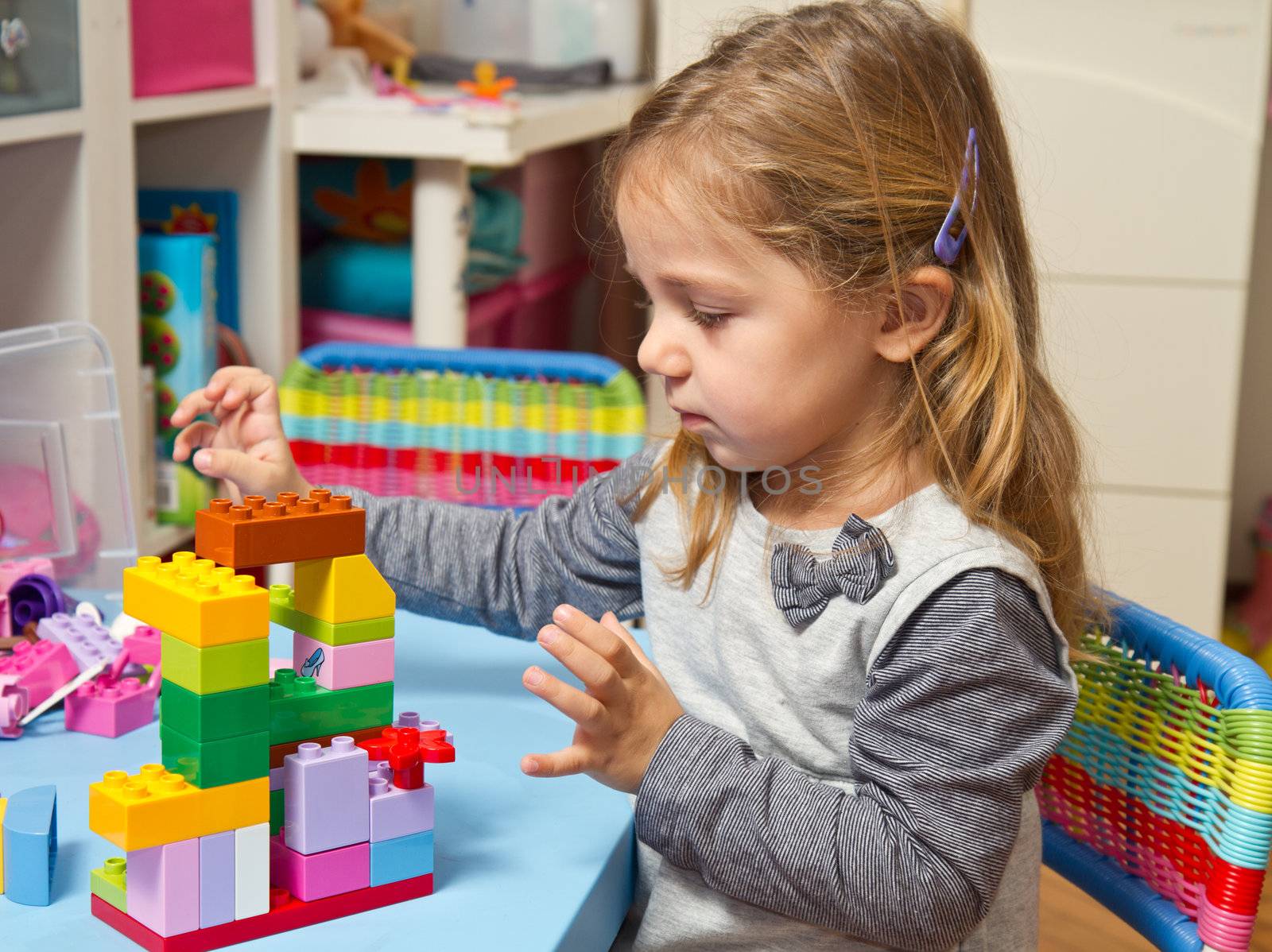 Little girl is playing with building bricks 