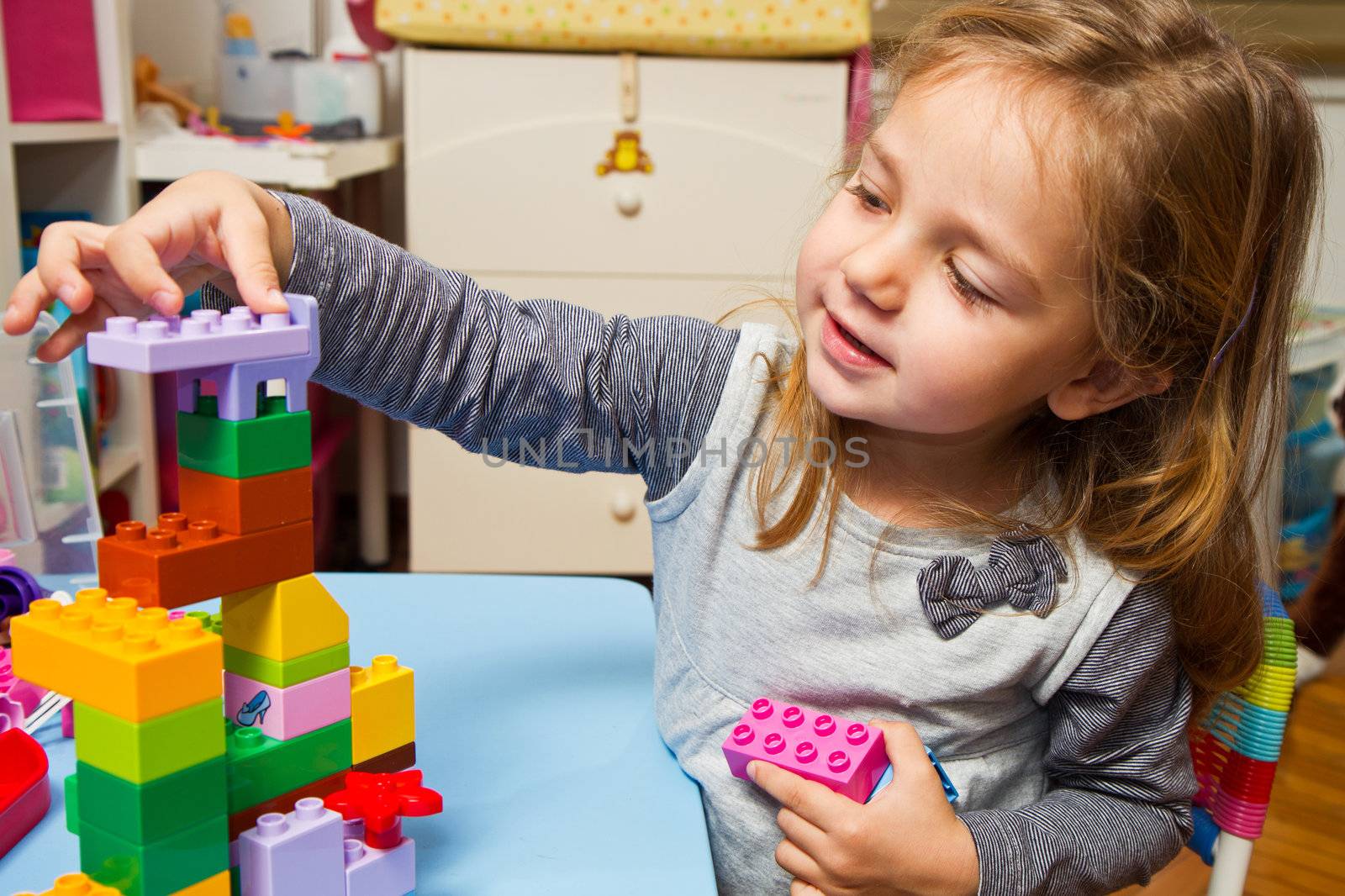 Little girl is playing with building bricks 