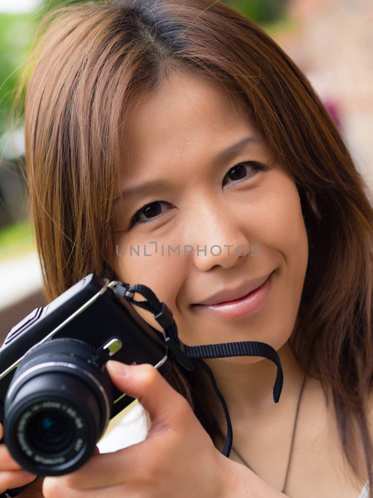 A young Japanese girl photographer holding up her compact digital camera