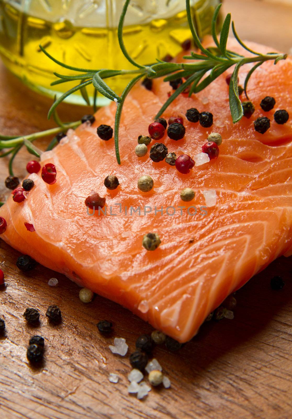 Fresh salmon fillet on wooden board with pepper and rosemary