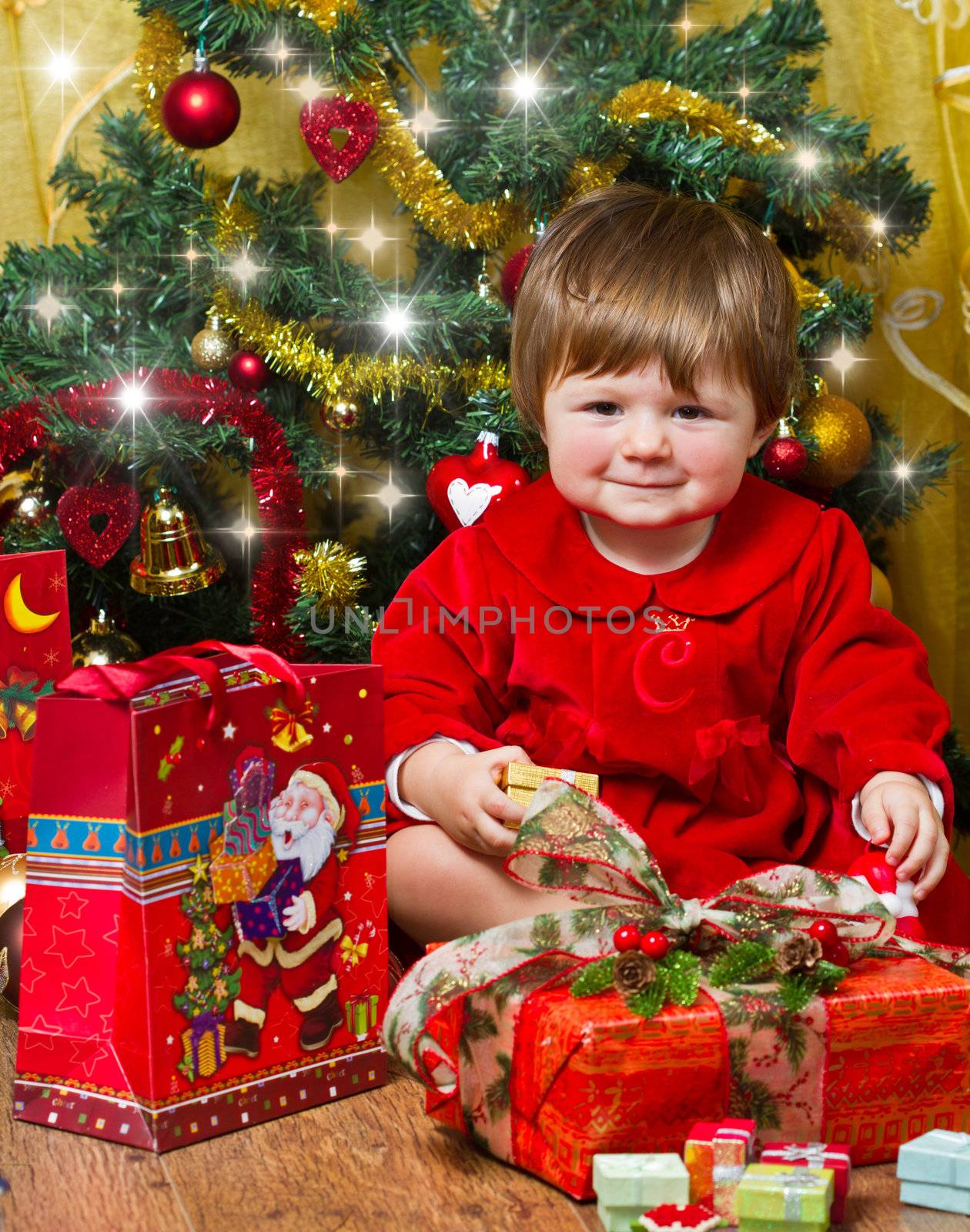 baby play with present box at Christmas tree by lsantilli
