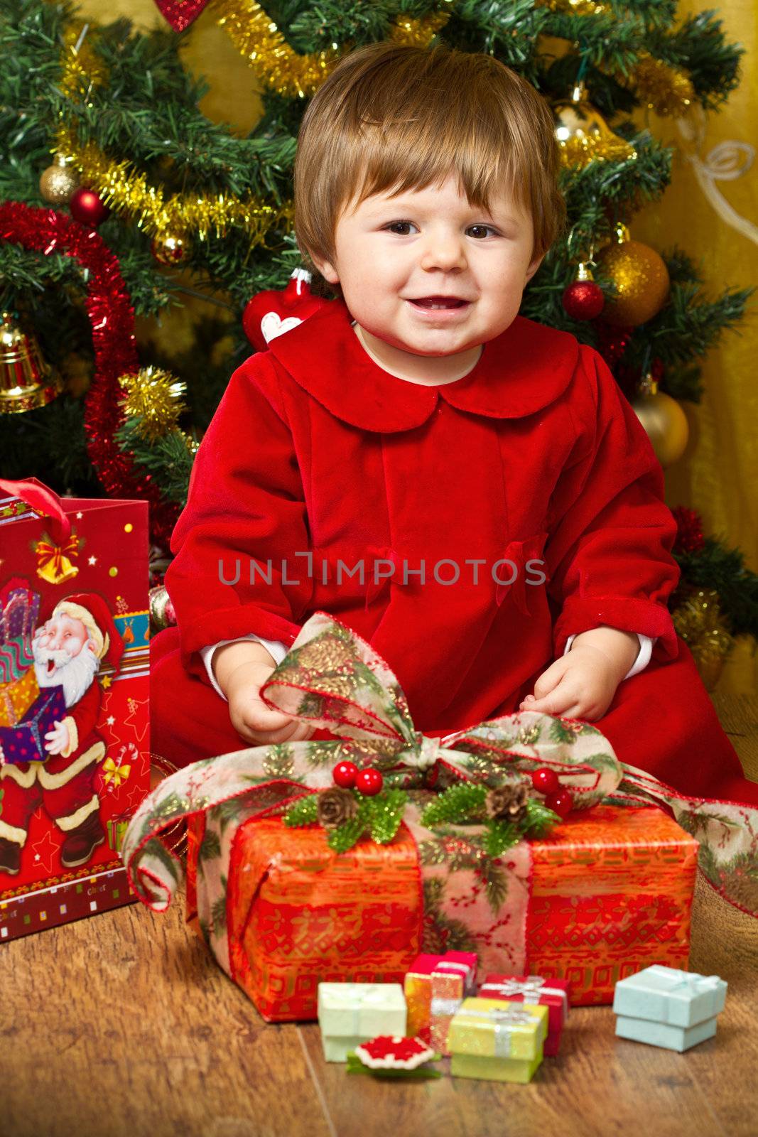 baby play with present box at Christmas tree by lsantilli