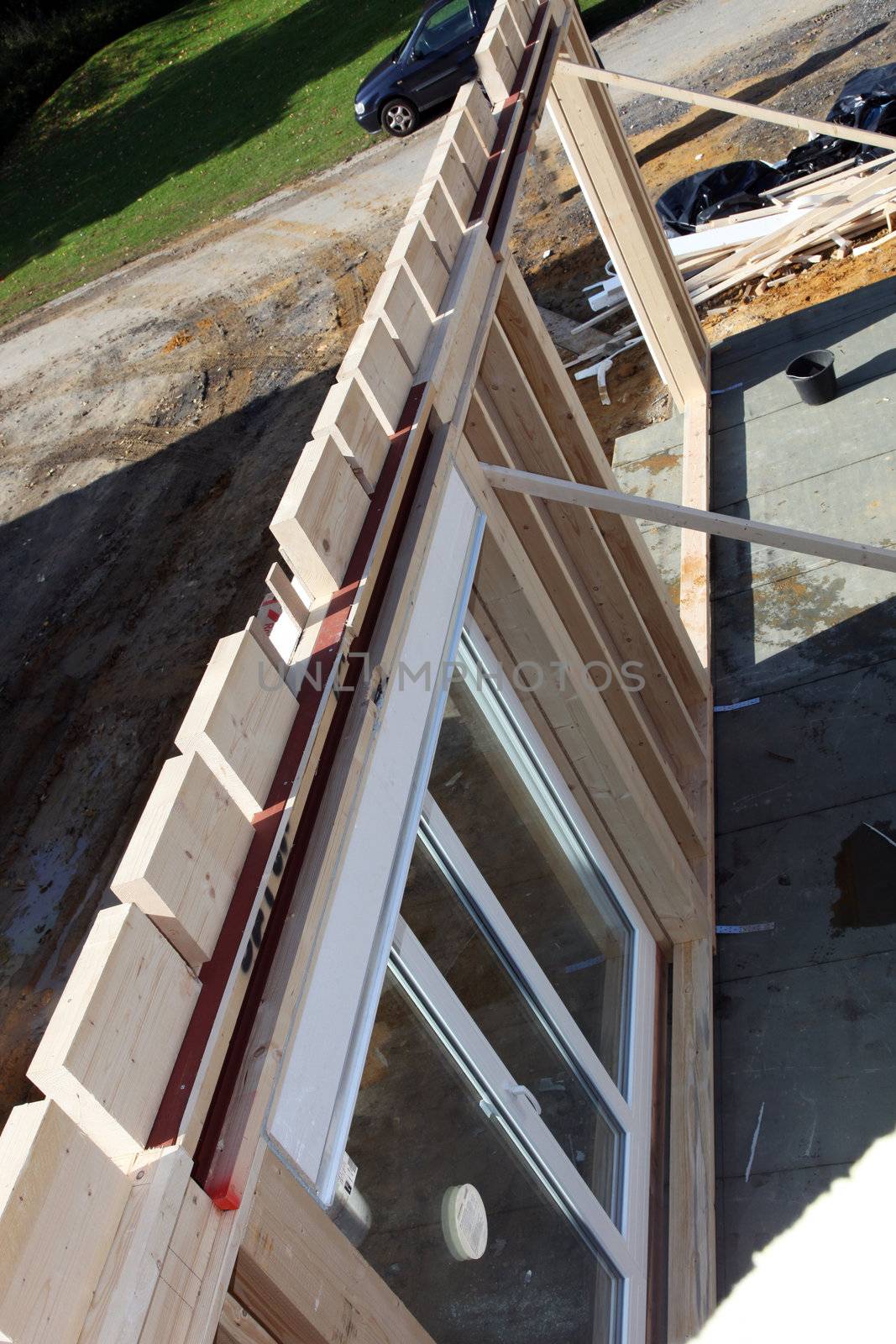 Newbuild timber wall with glass doors being held upright by supports during installation on a residential building site