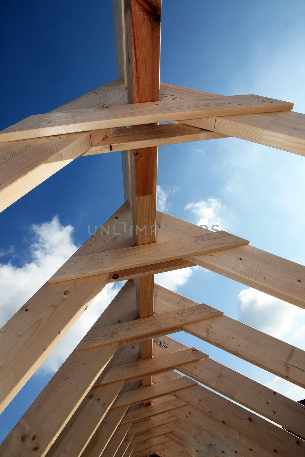 View of blue sky through the wooden beams of a roof at construction site