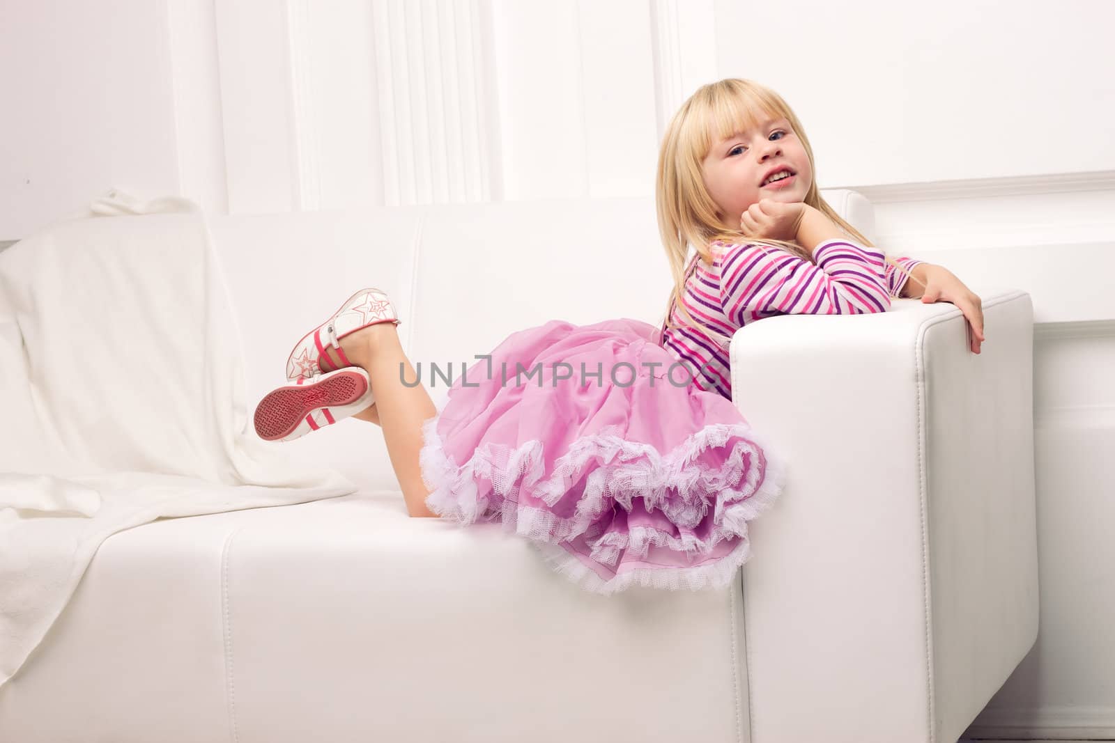 Little cute girl posing happily on sofa