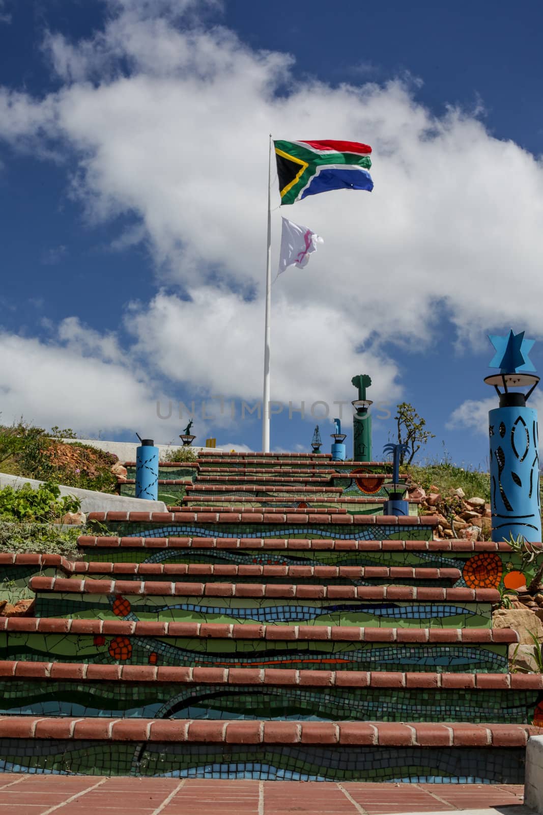 A giant South African flag and a white flag with pink ribbon waving over the city of Port Elizabeth around the famous lighthouse area