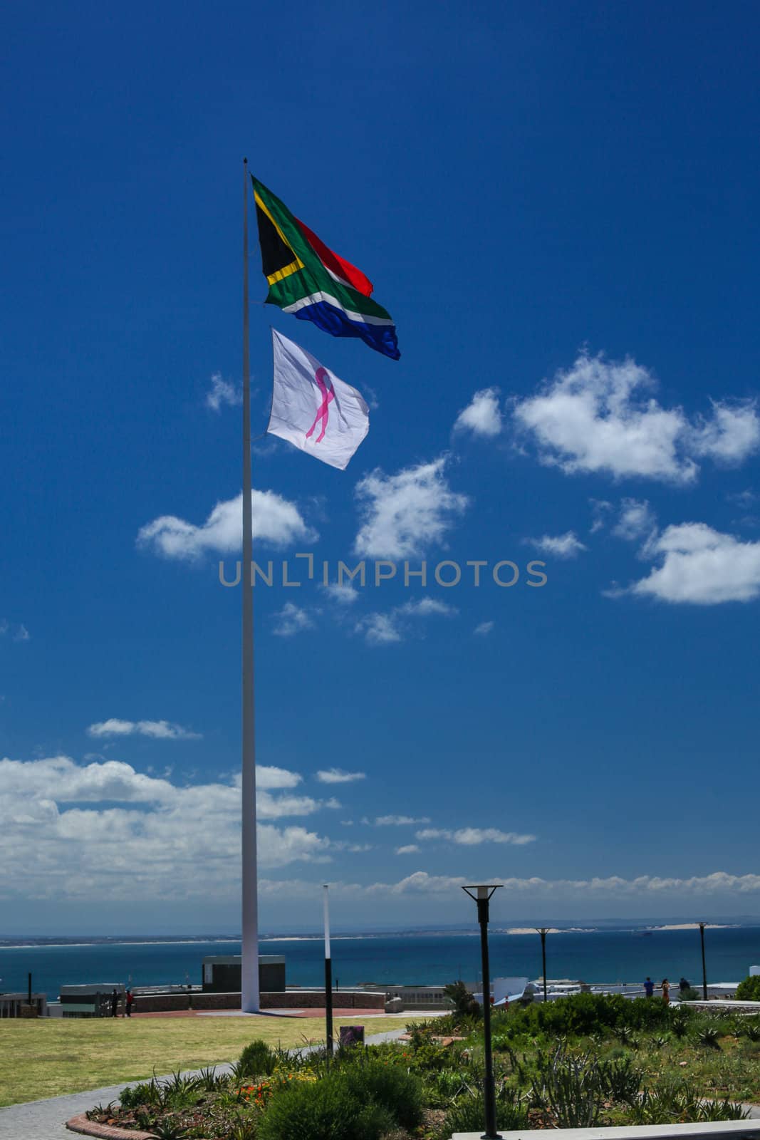 A giant South African flag and a white flag with pink ribbon waving over the city of Port Elizabeth around the famous lighthouse area