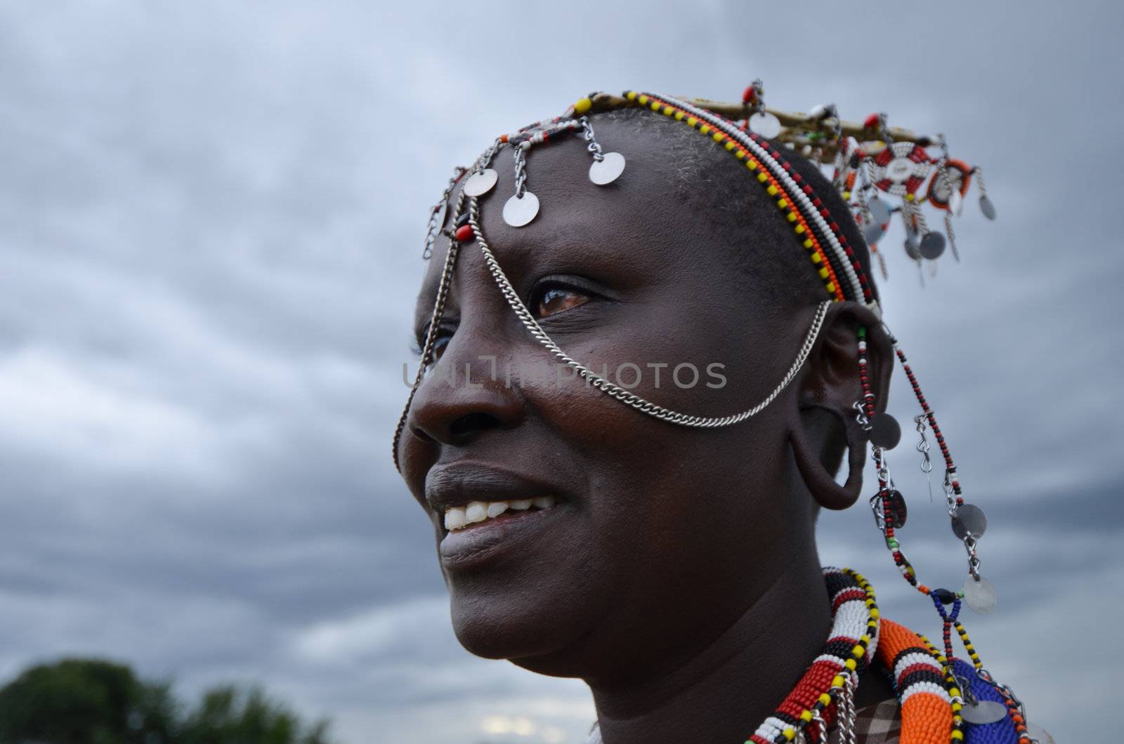 Village  Masai Mara, Kenya – October  17, 2011: Masai woman is seen in his ceremonial dress. He is meeting visitors to his village where he demonstrates traditional culture. She is located in the southwestern region of the Masai Mara in Kenya.
