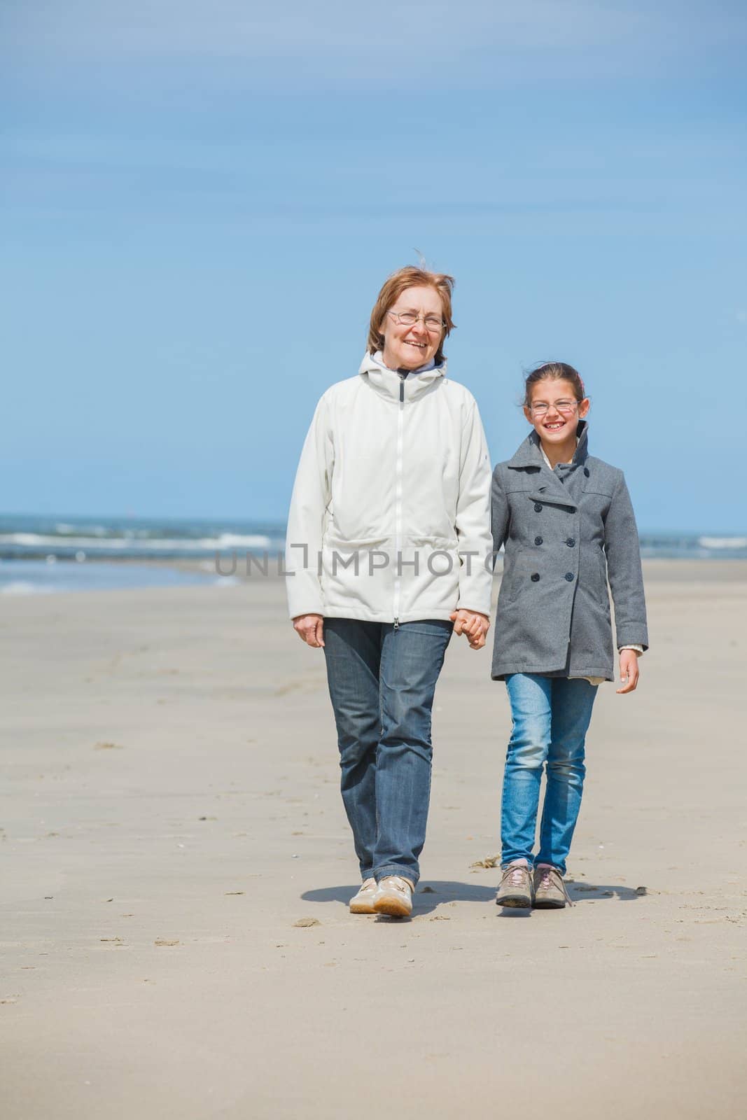 Beautiful girl and her grandmother walking on the beach. Holland