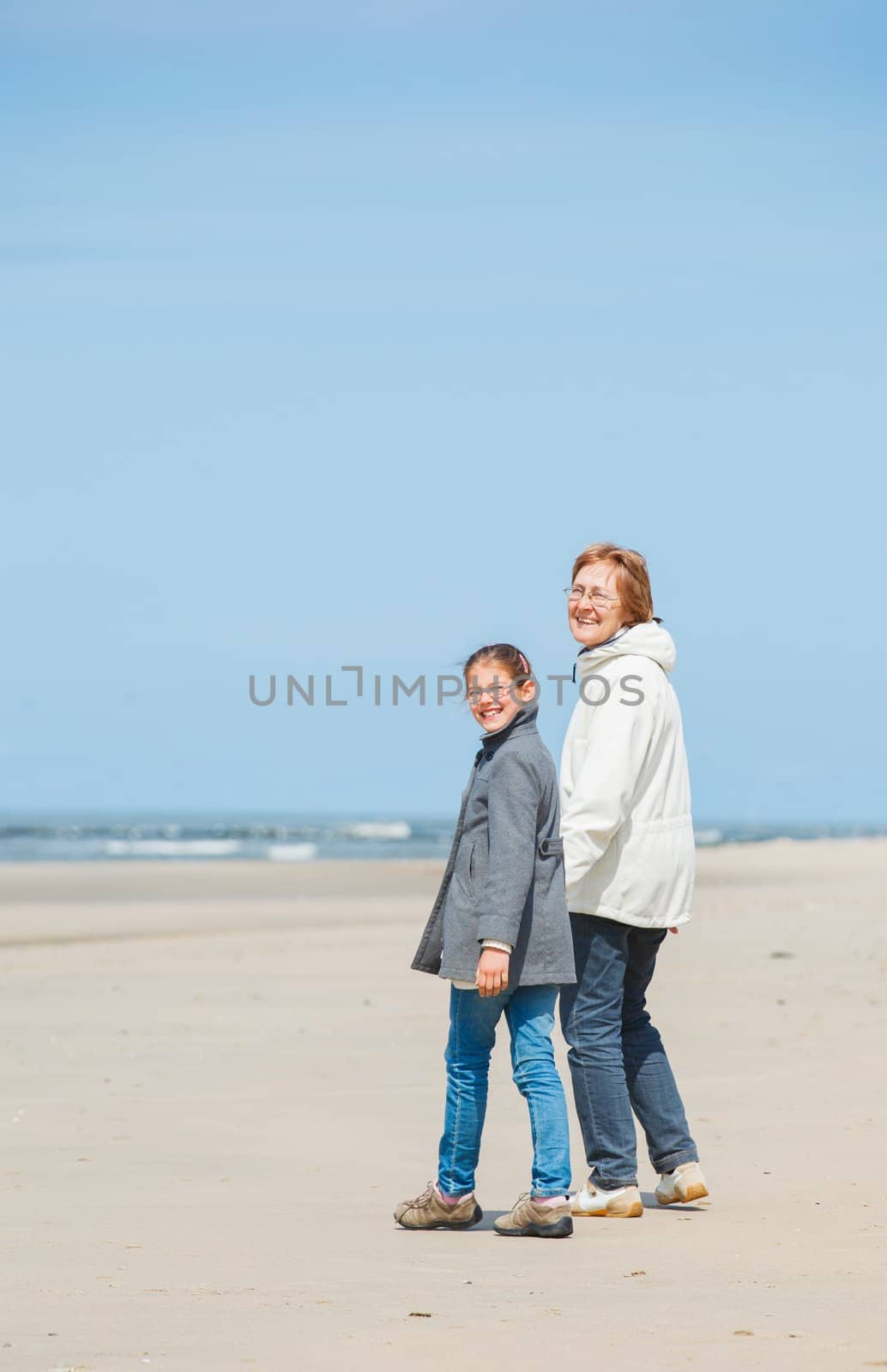 Beautiful girl and her grandmother walking on the beach. Holland