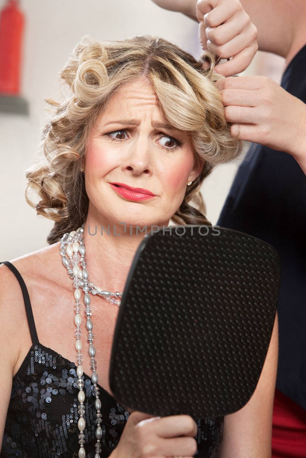 Dissatisfied pretty woman in salon holding mirror