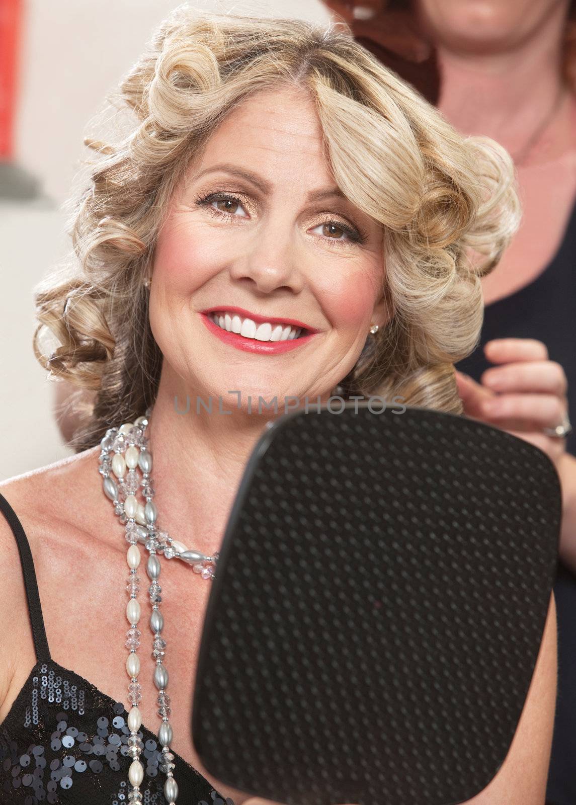 Attractive middle aged female with mirror in hair salon