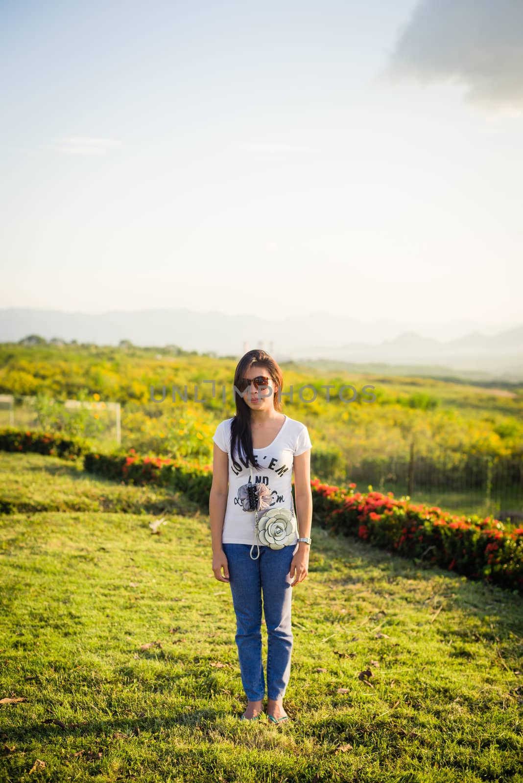 asian girl standing on grass field with sunlight and sky on the background