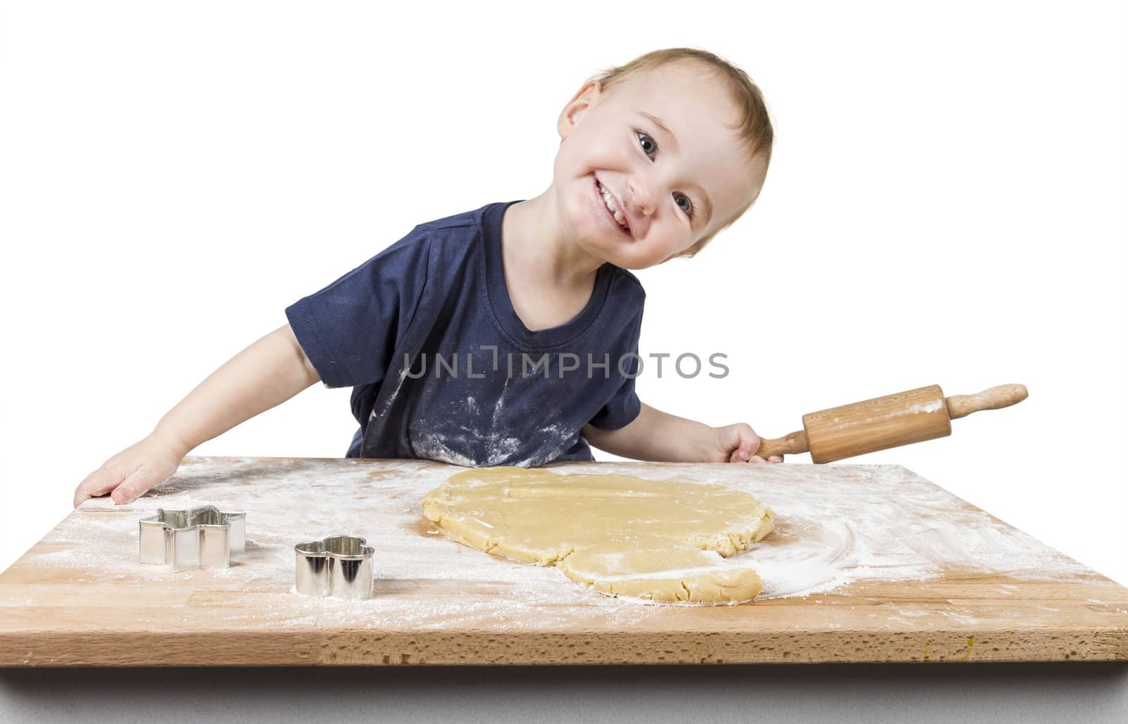 young child making cookies on small wooden desk