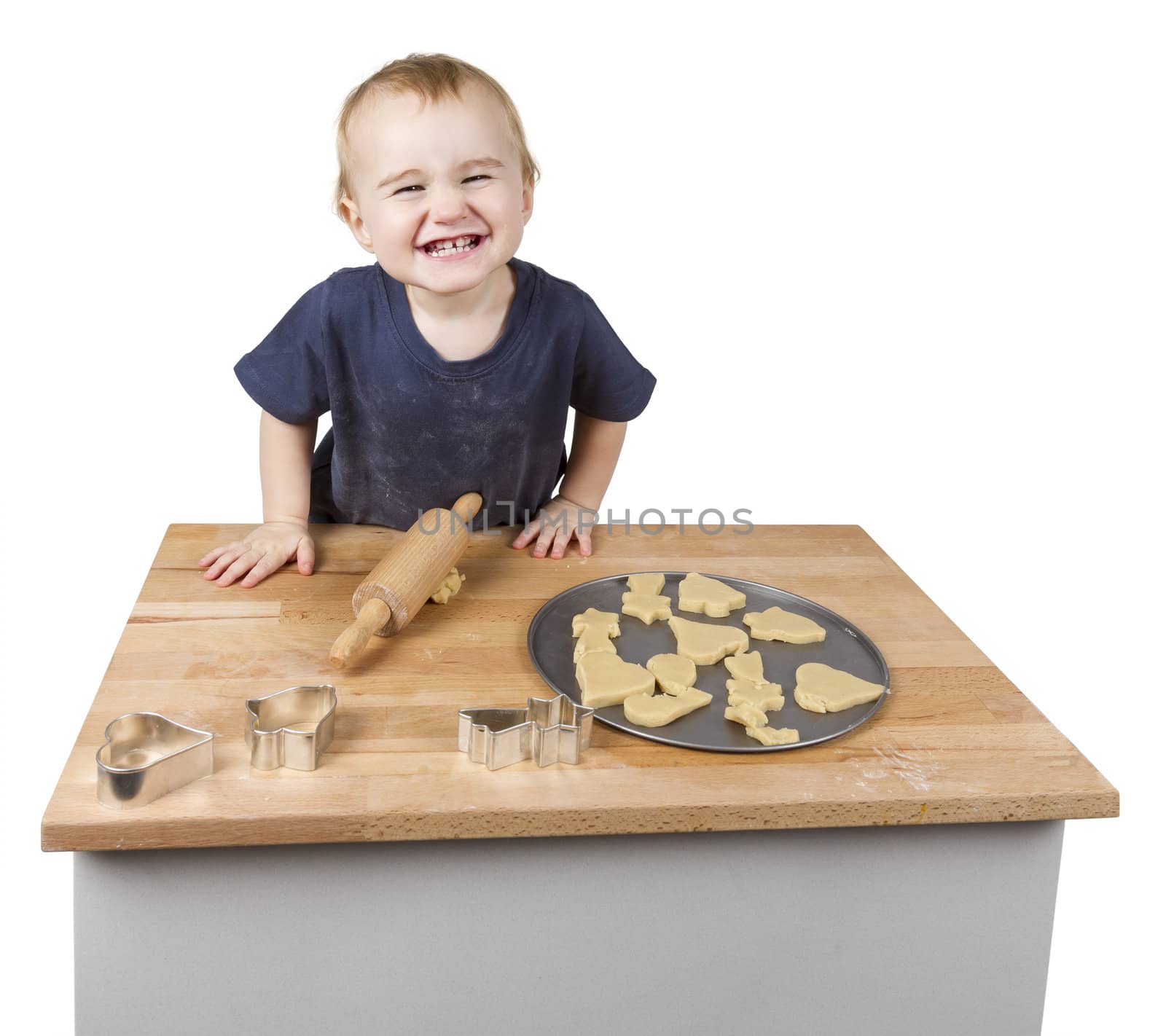 young child making cookies on small wooden desk