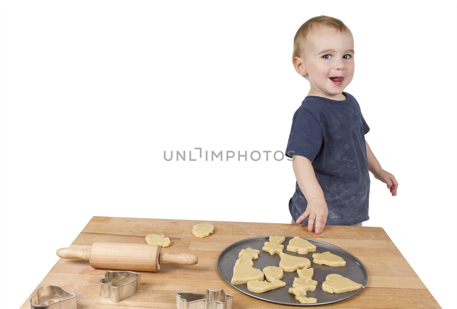 young child making cookies on small wooden desk