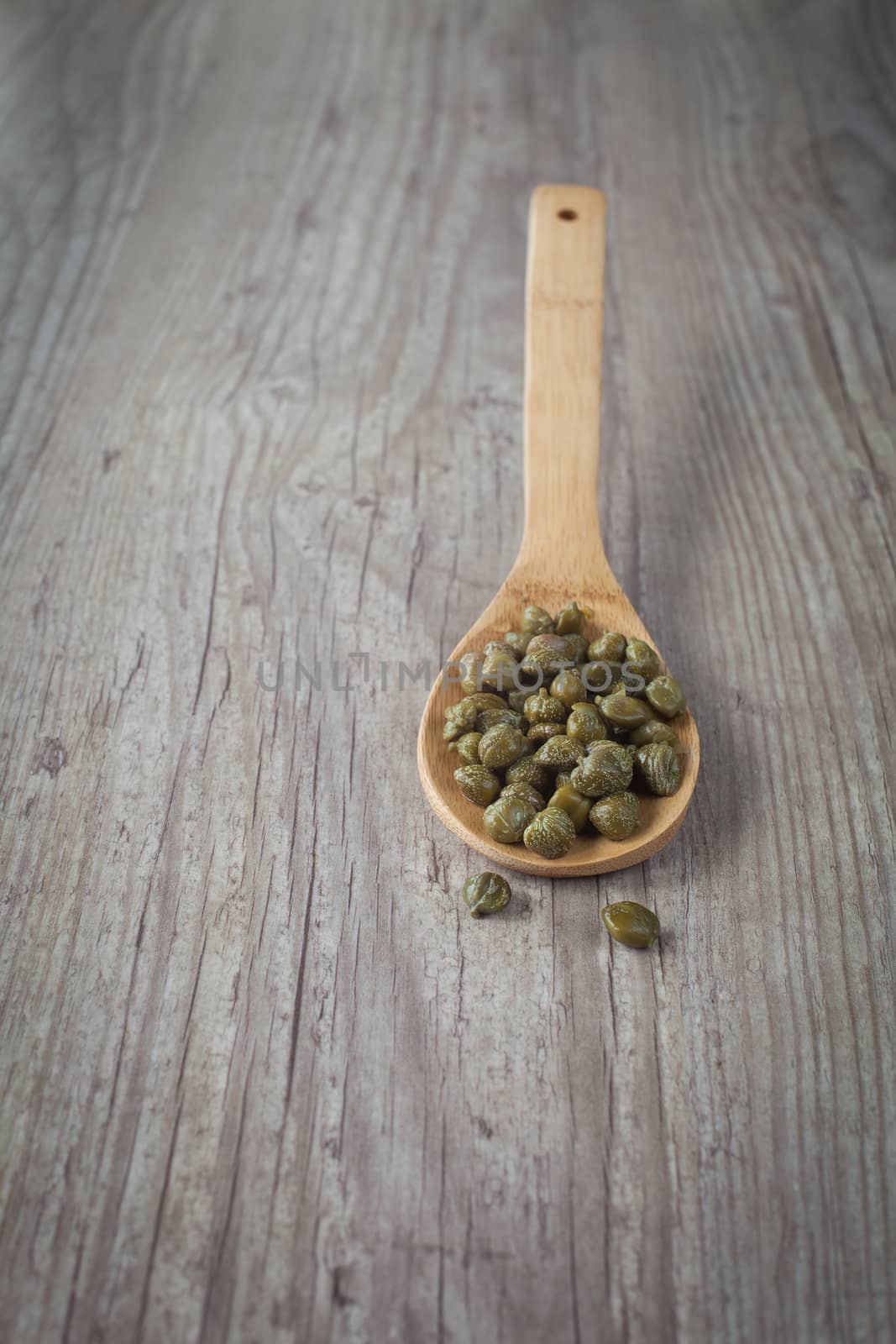 Bunch of fresh capers on a wooden spoon