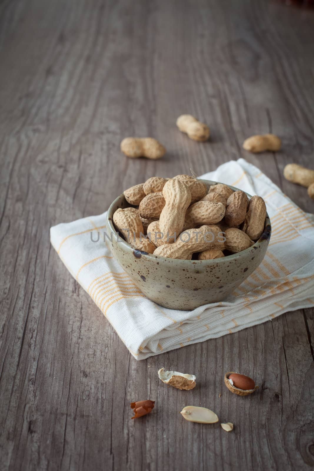 Bunch of peanuts in a bowl on wooden table