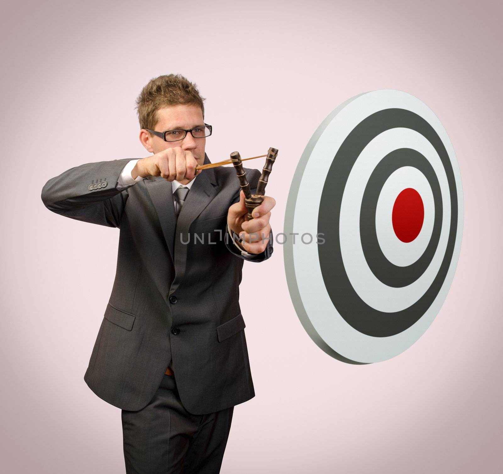 Businessman with slingshoot aiming target