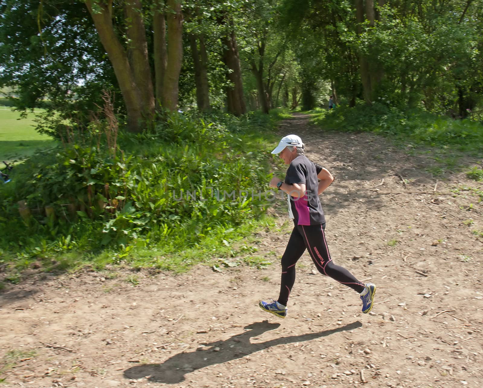 Older woman running trail race in countryside