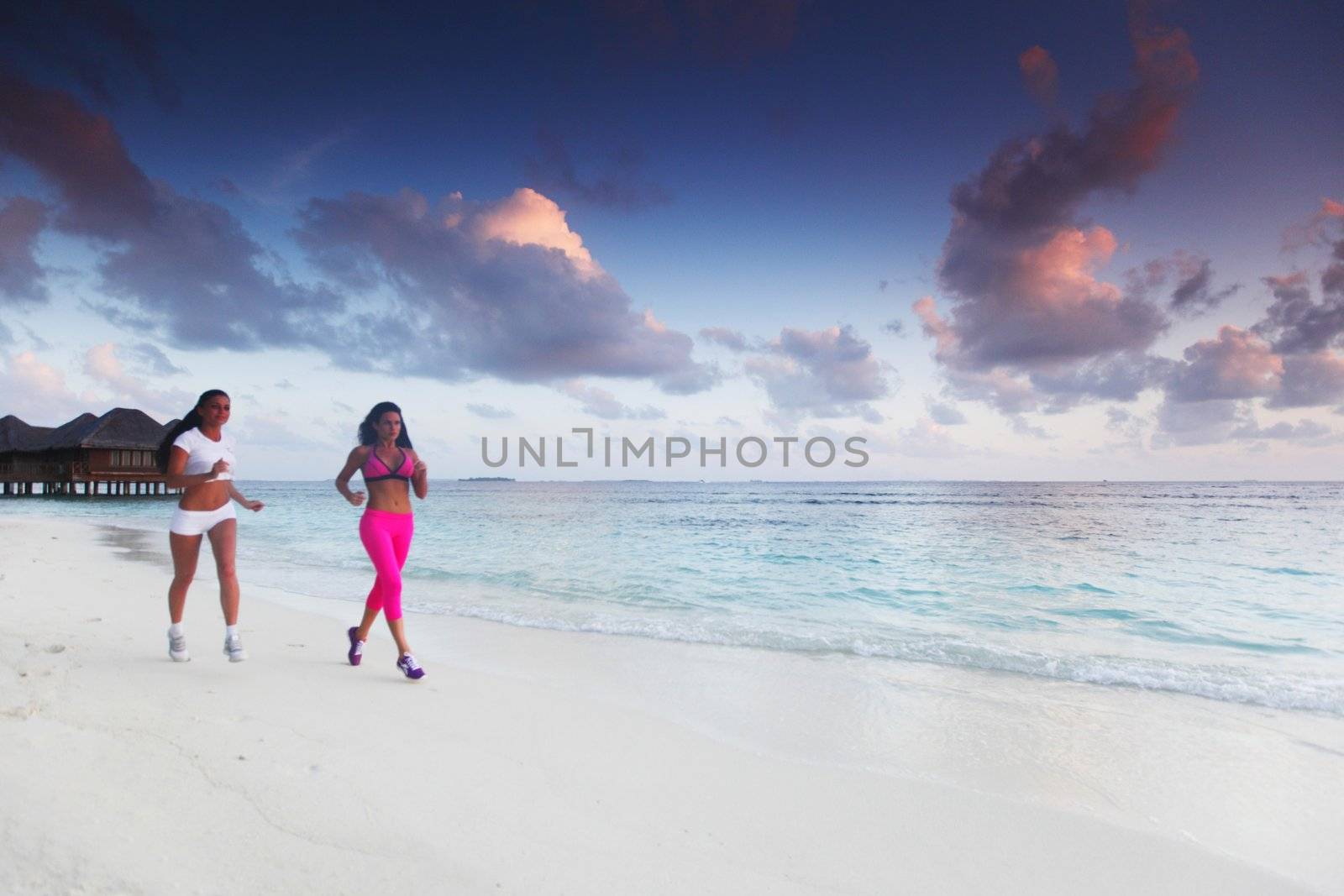Fitness sport women running on beach at sunset