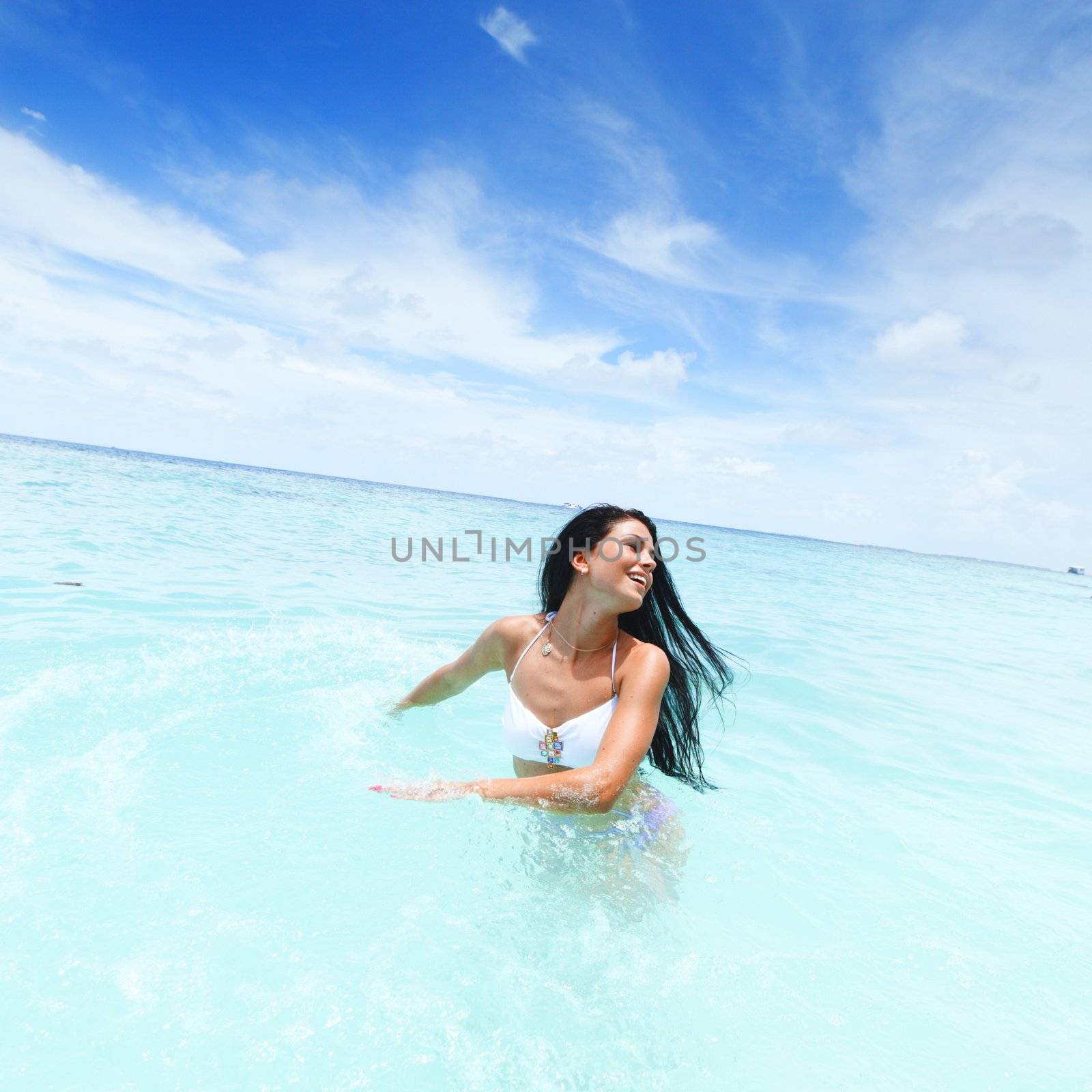 Woman splashing in sea by Yellowj