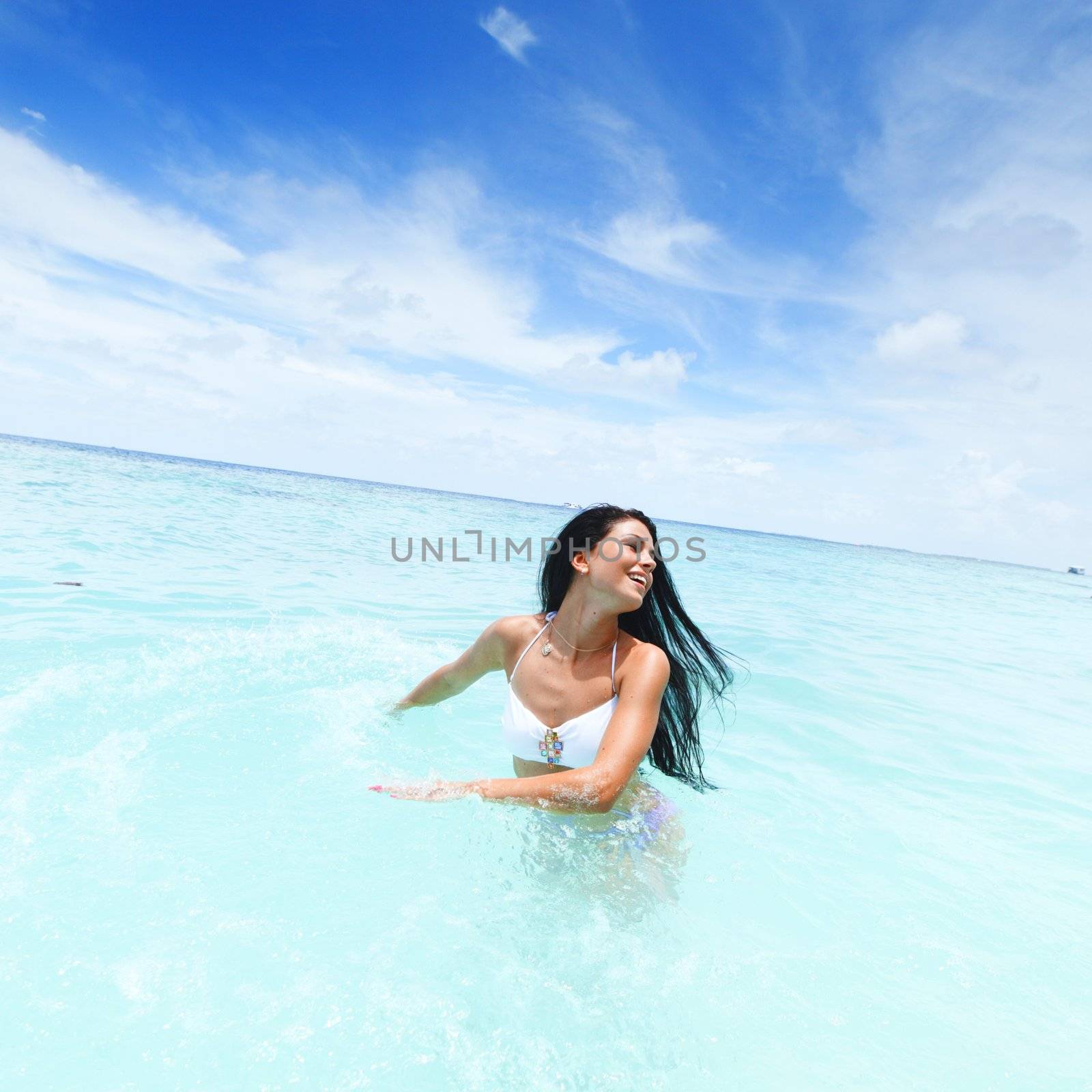 Cheerful pretty young woman splashin in sea