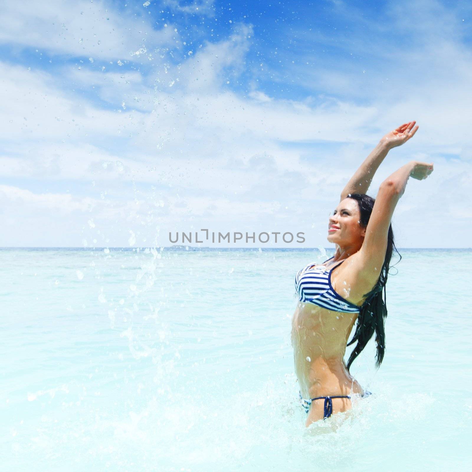 Cheerful pretty young woman splashin in sea