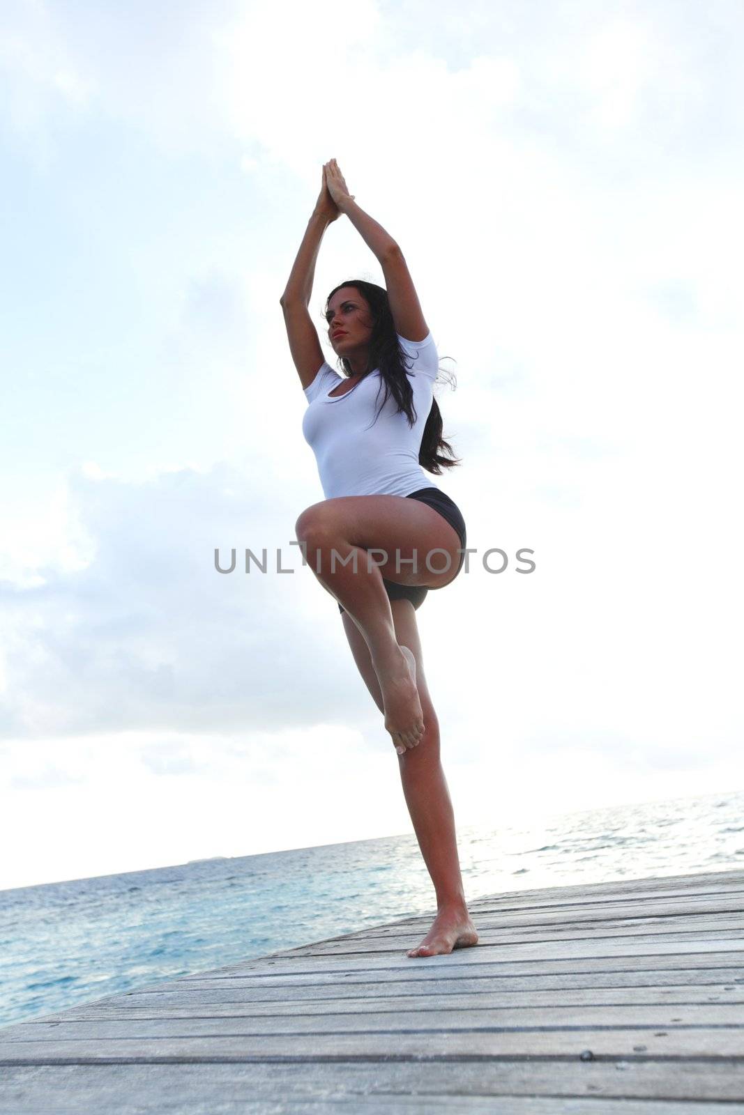 Yoga woman on wooden bridge near sea