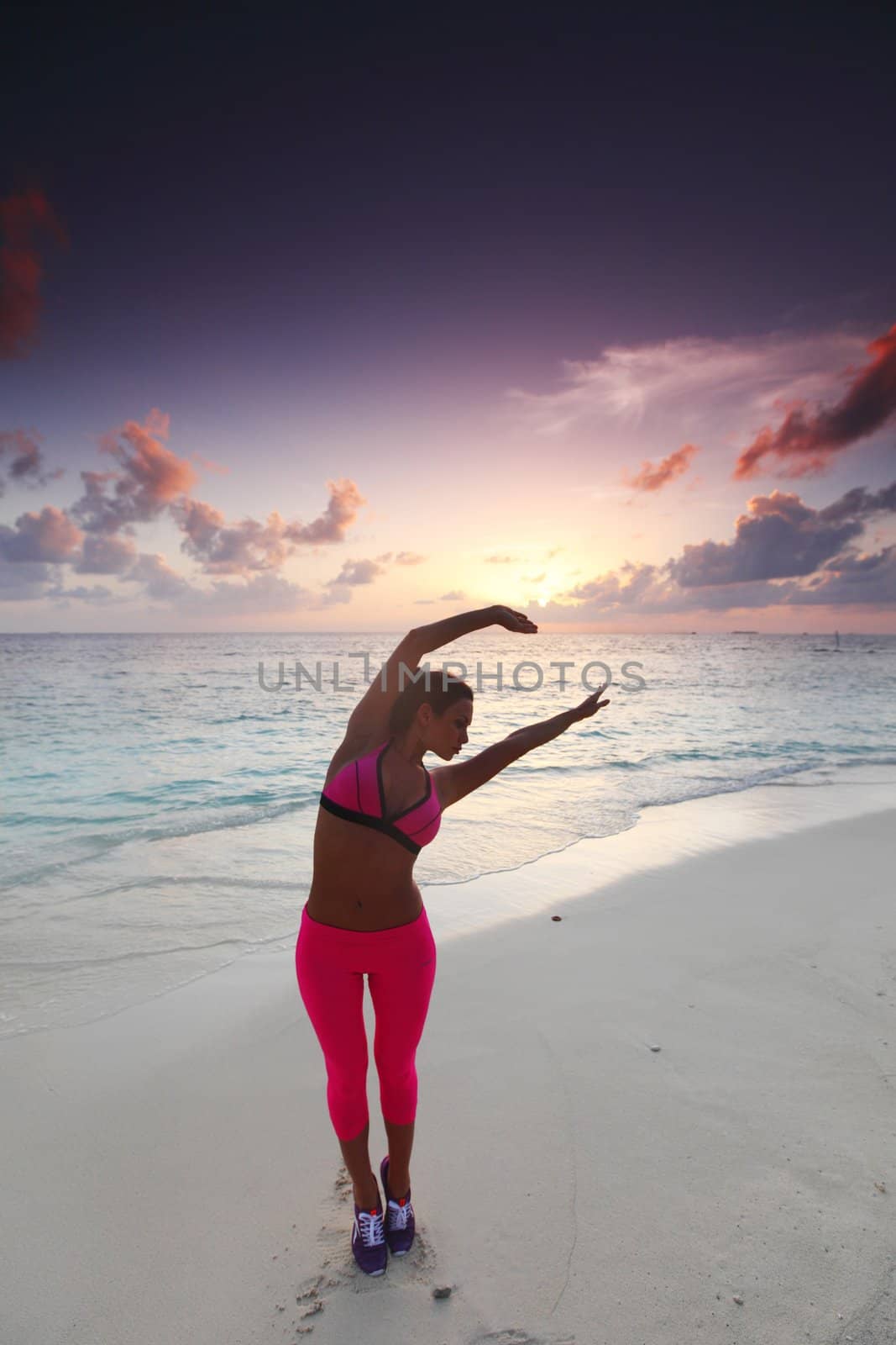 Beautiful fit woman stretching on beach in the morning