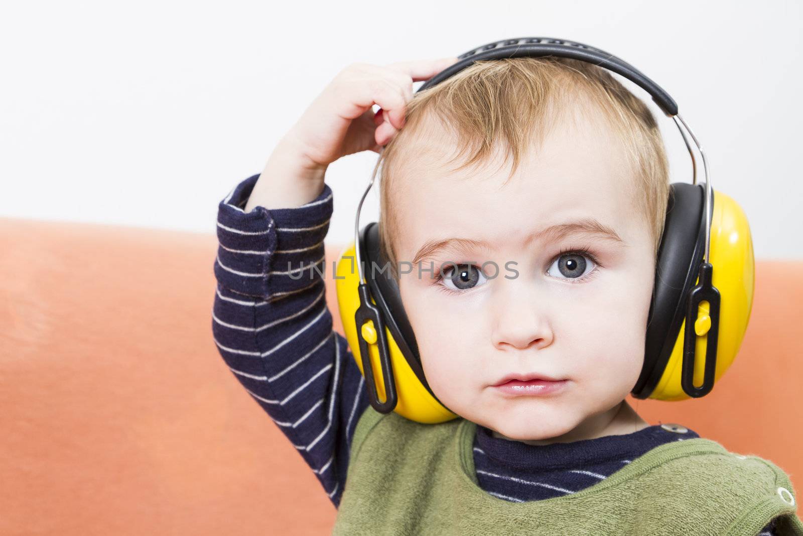 young child on couch with yellow earmuffs